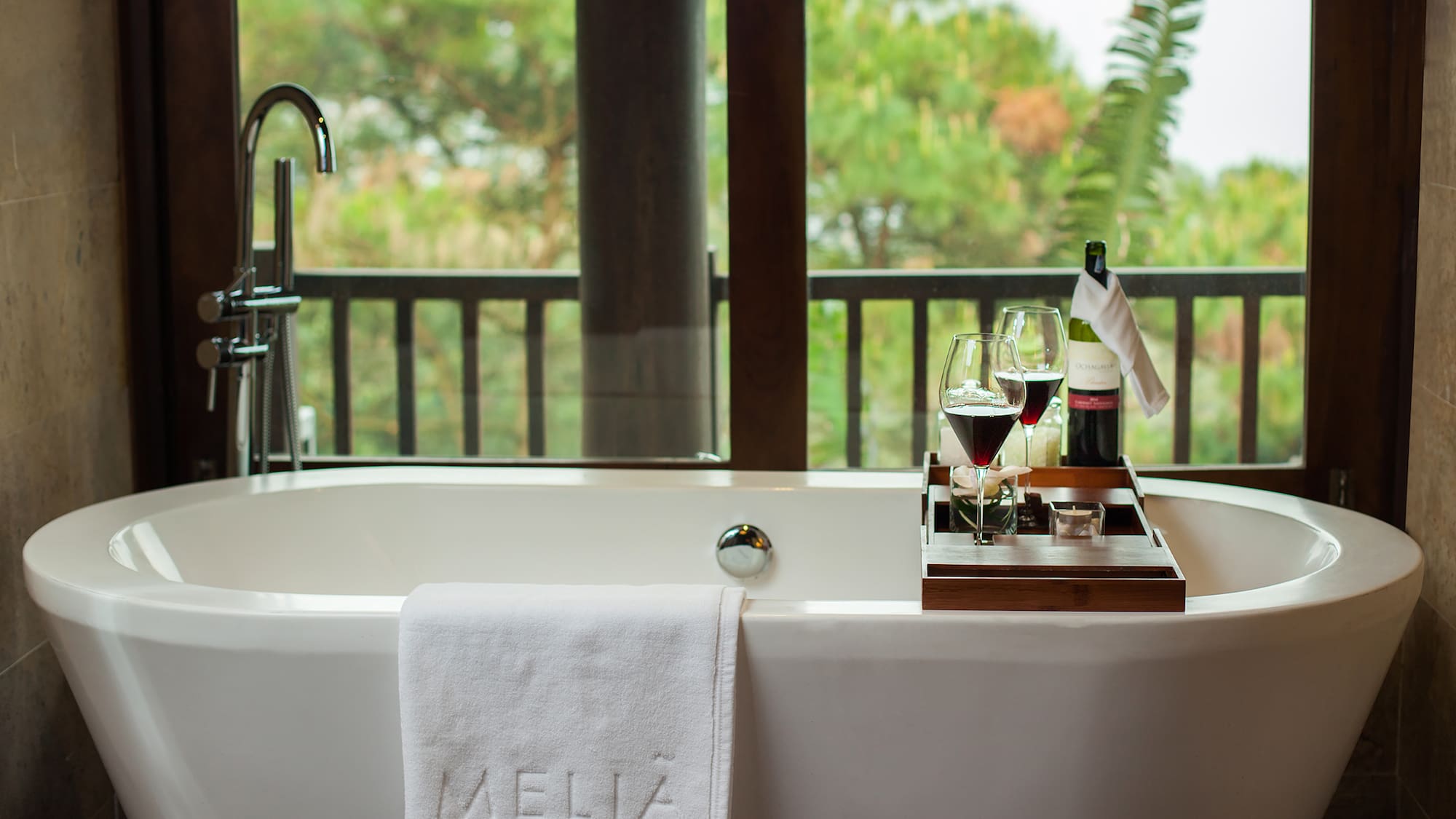a bathtub with wine glasses and a tray on it