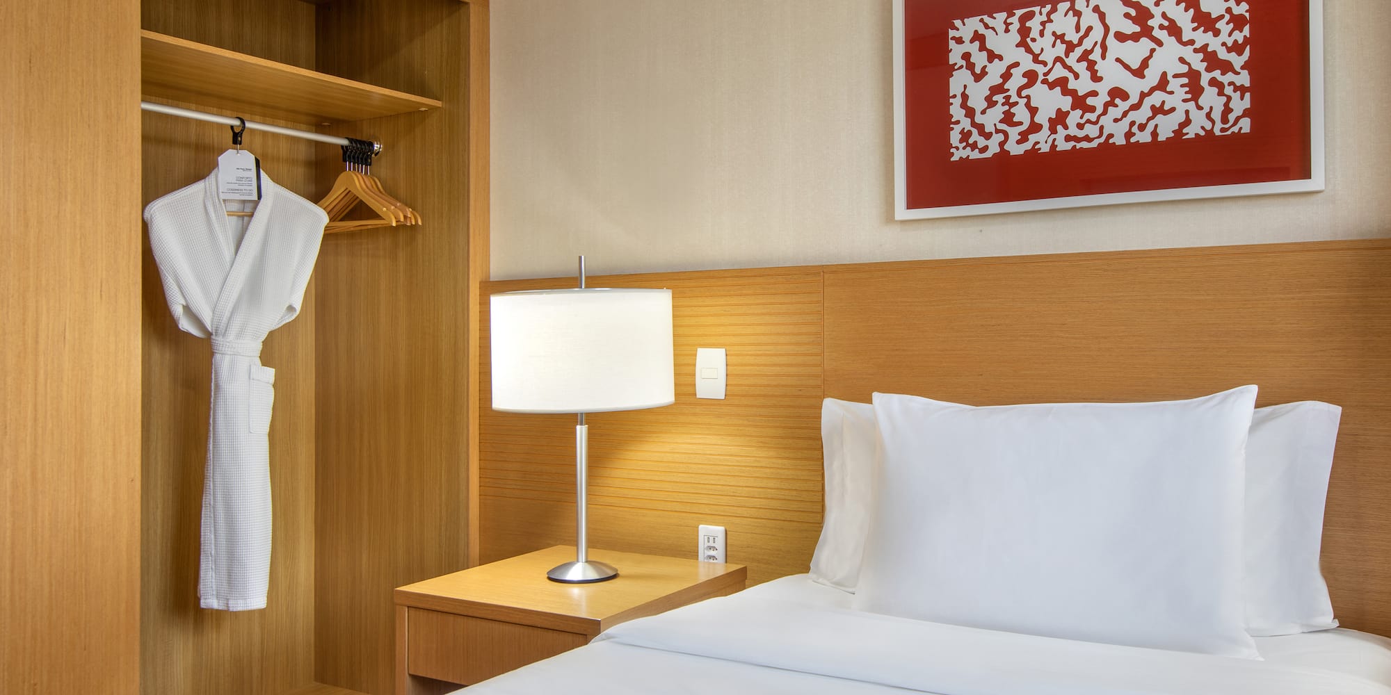 a bed with a white robe and a lamp in a room