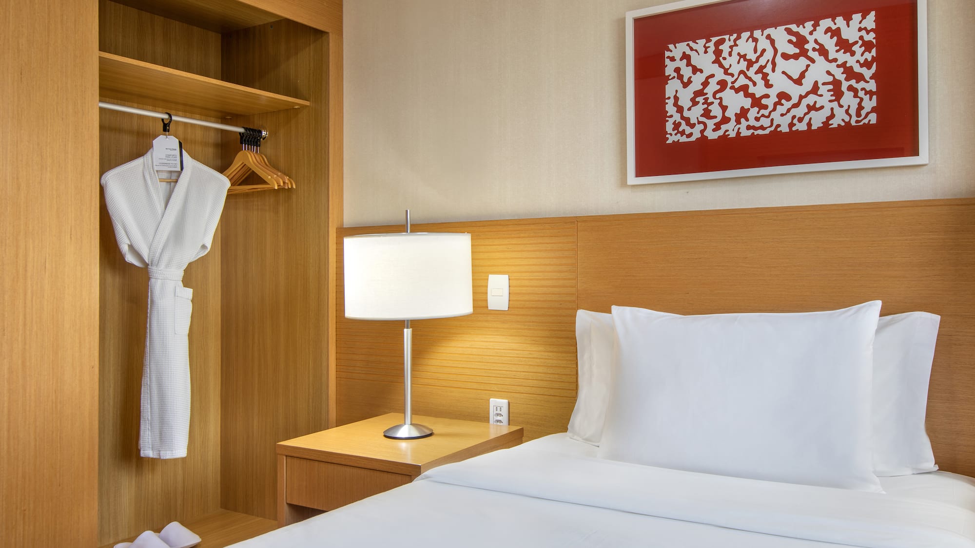 a bed with a white robe and a lamp in a room