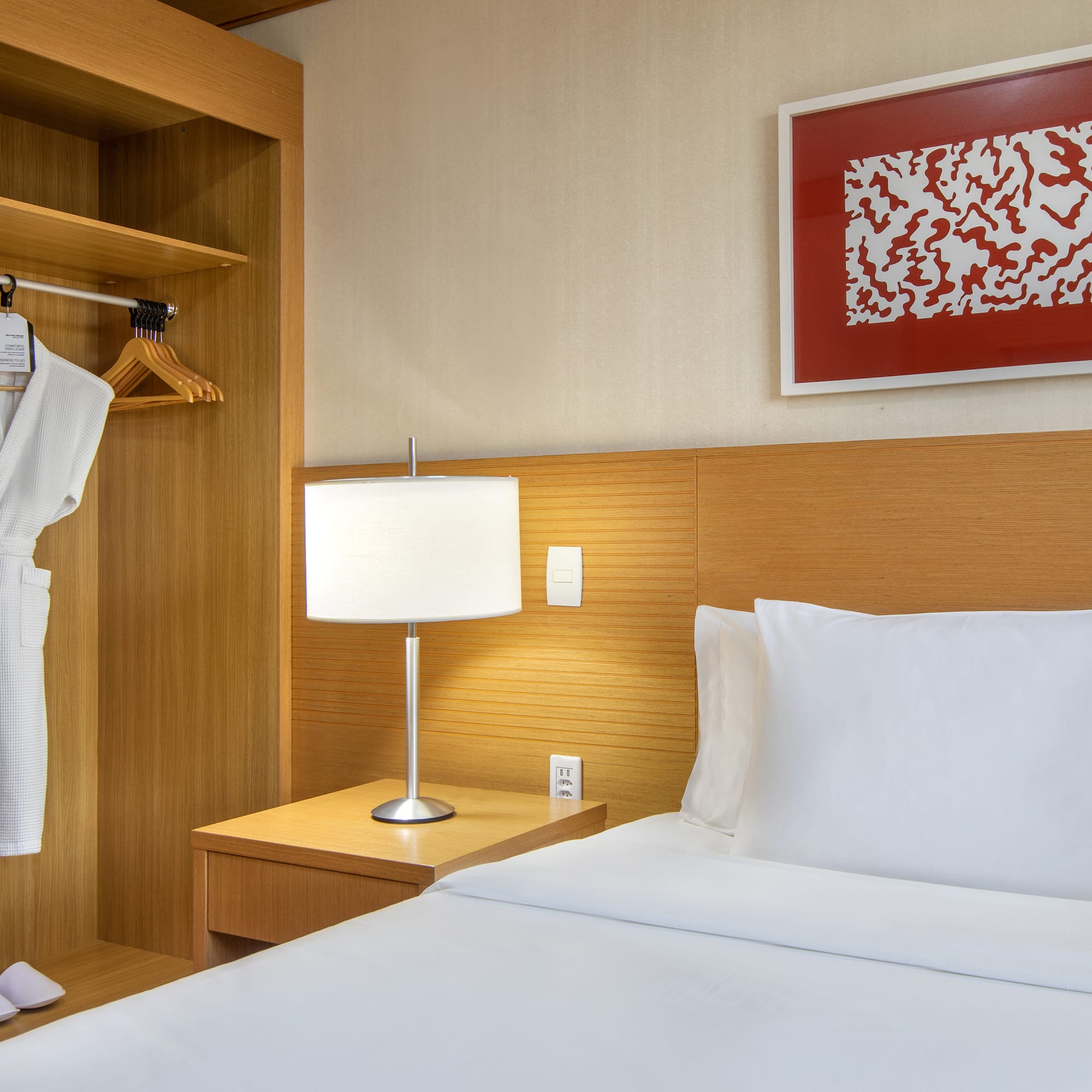 a bed with a white robe and a lamp in a room