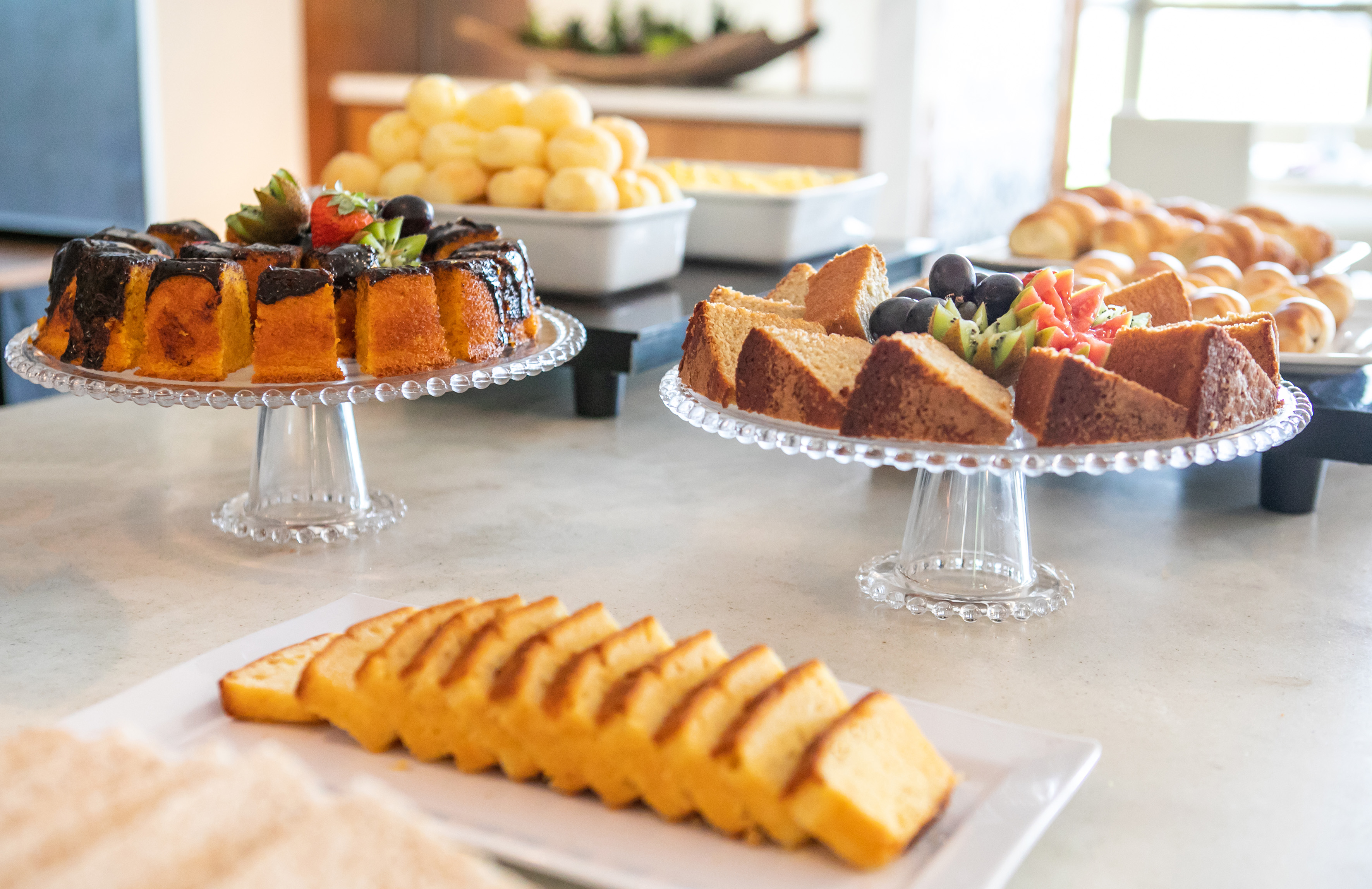 Sweet breakfast buffet with chocolate cake, sliced cakes, and fruits.
