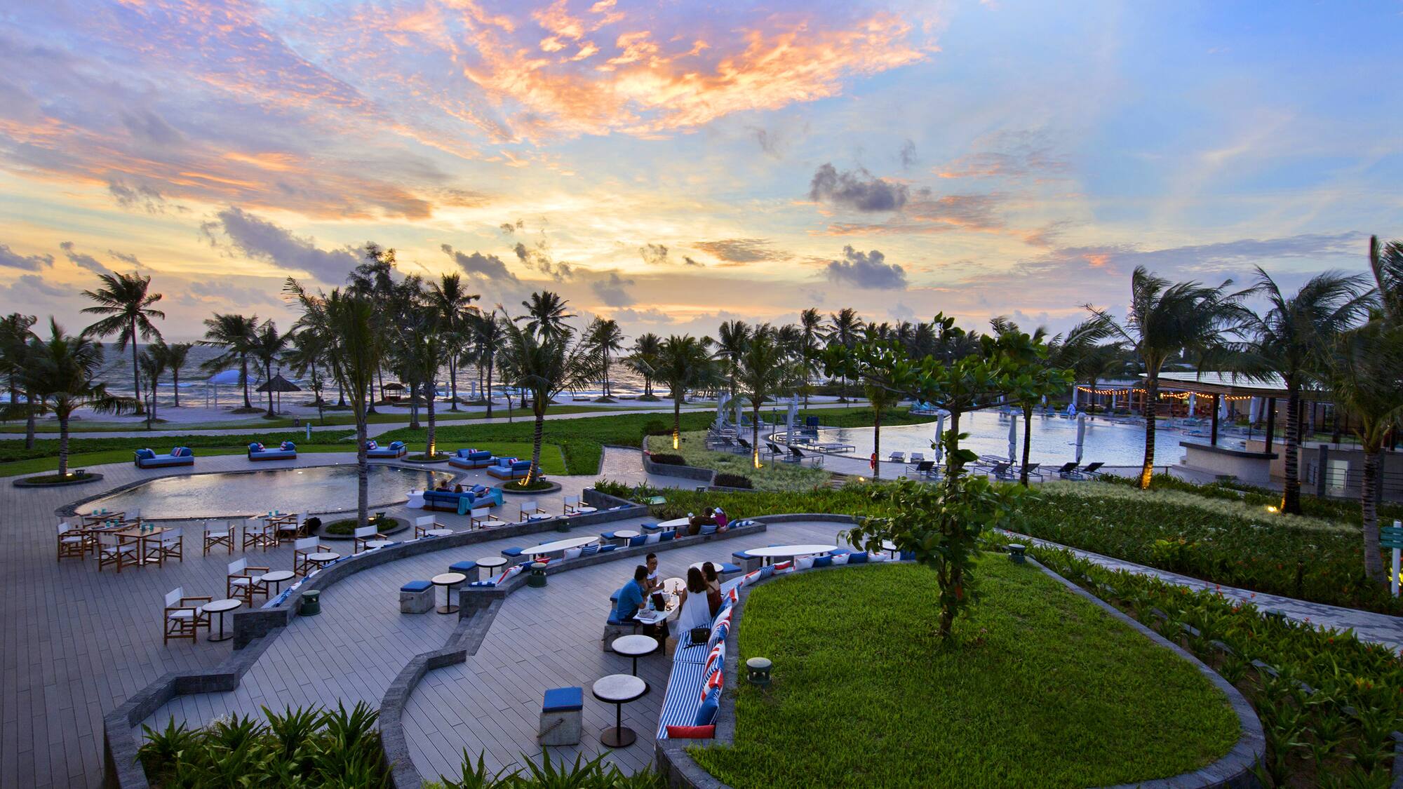 a group of people sitting at tables and chairs in a park