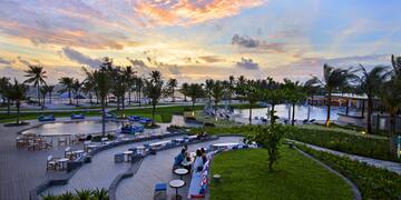 a group of people sitting at tables and chairs in a park