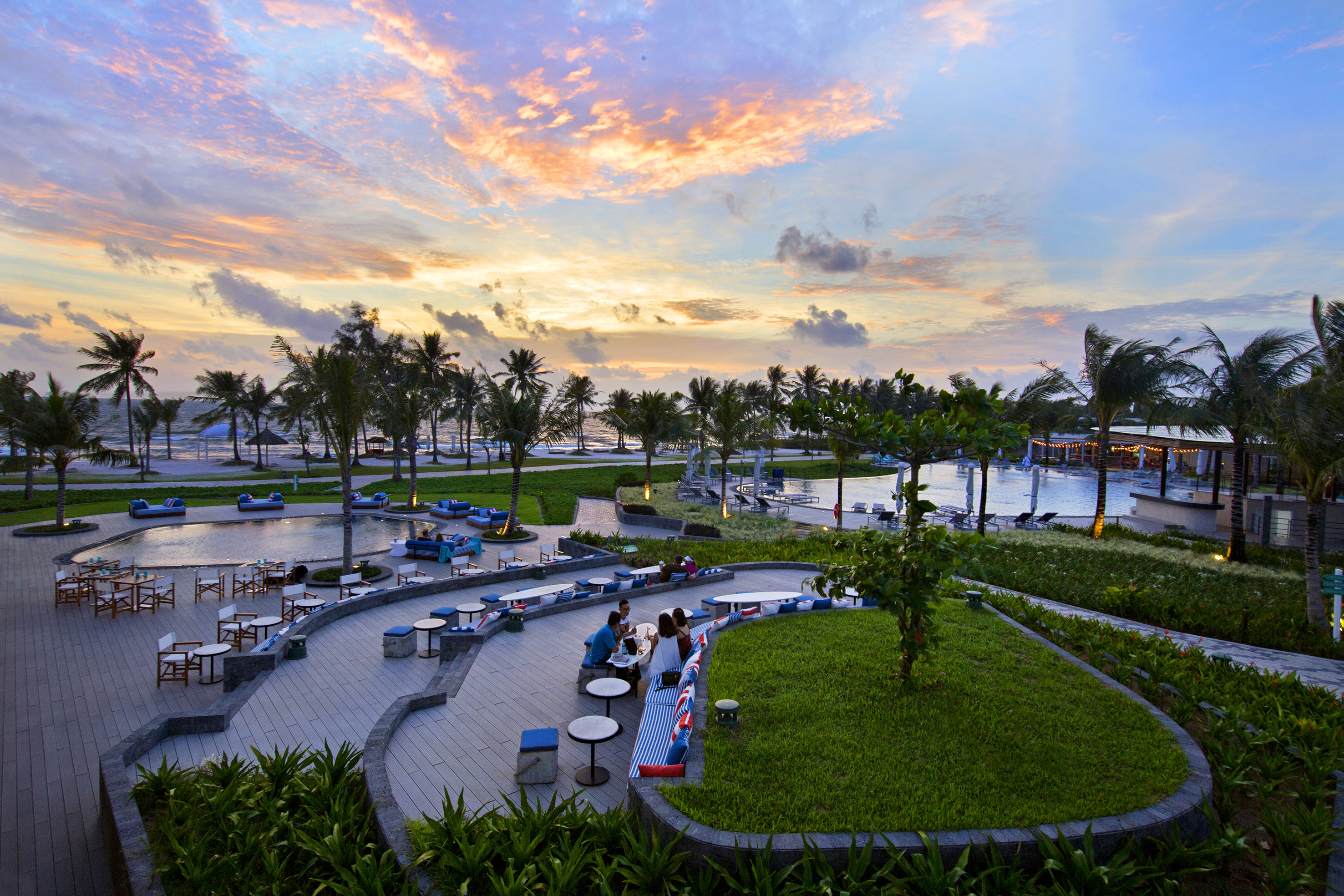 a group of people sitting at tables and chairs in a park