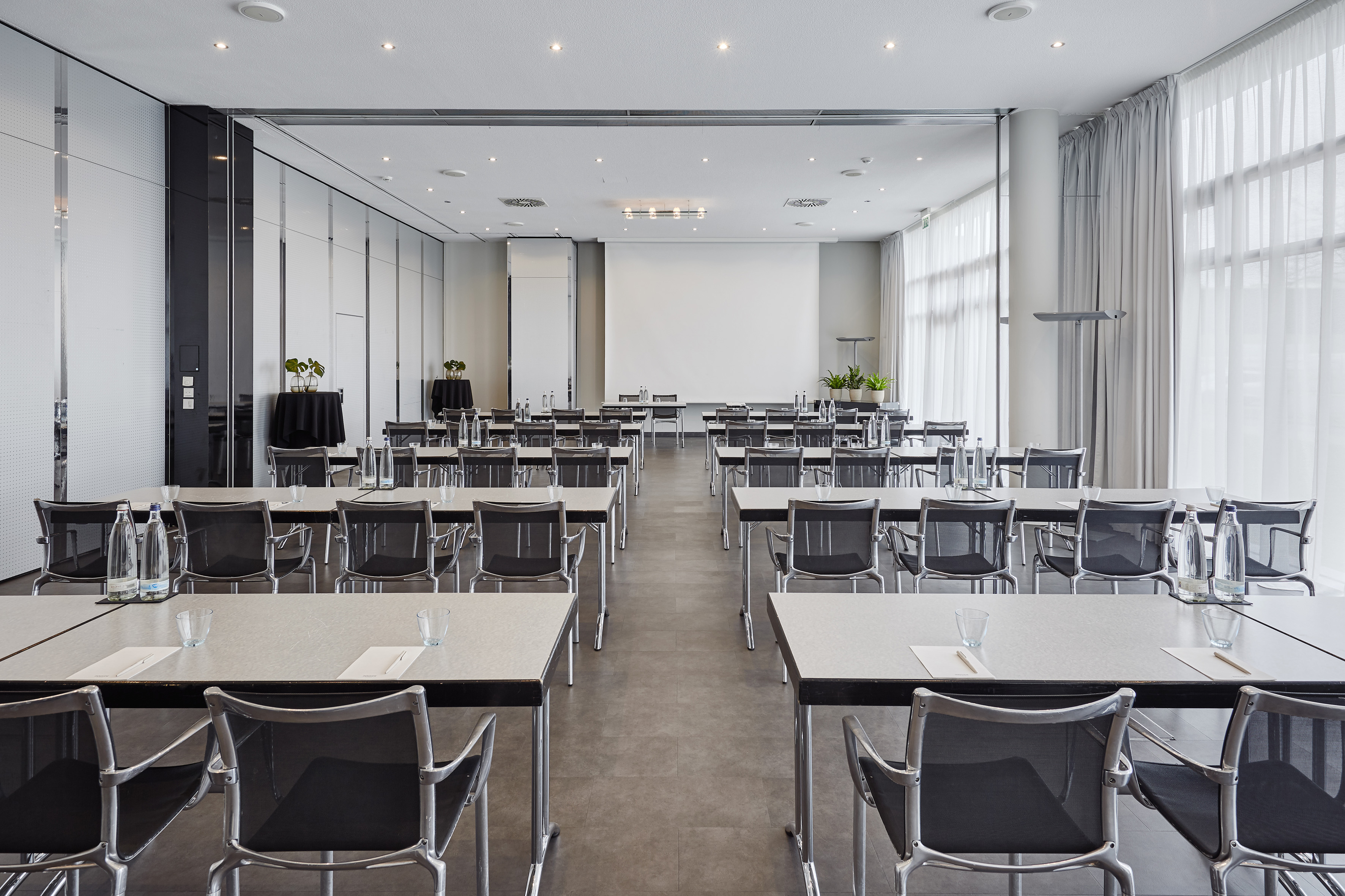 Modern conference room with classroom tables, chairs, and projector screen.
