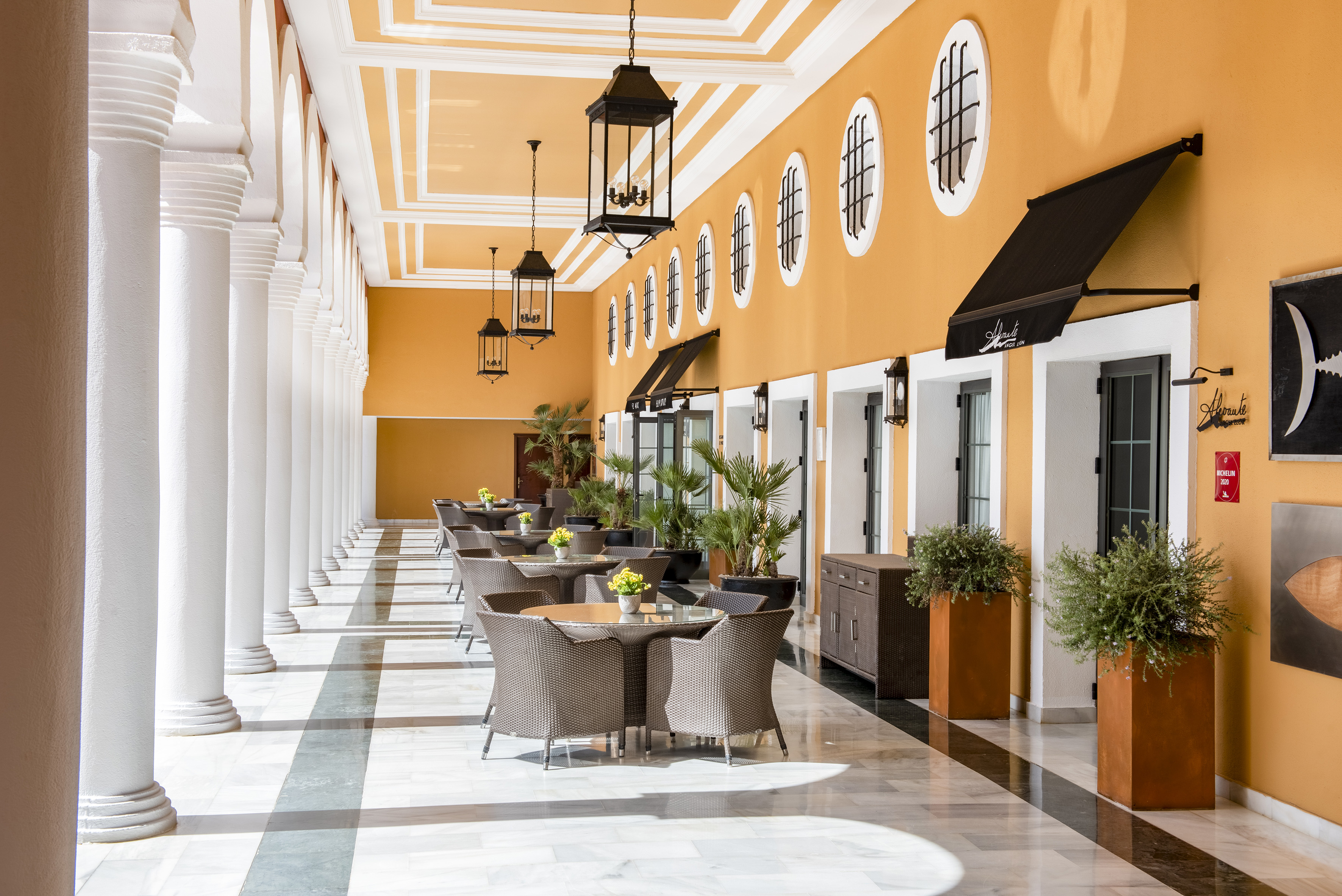 Hotel patio restaurant with white columns, orange walls, and outdoor seating.