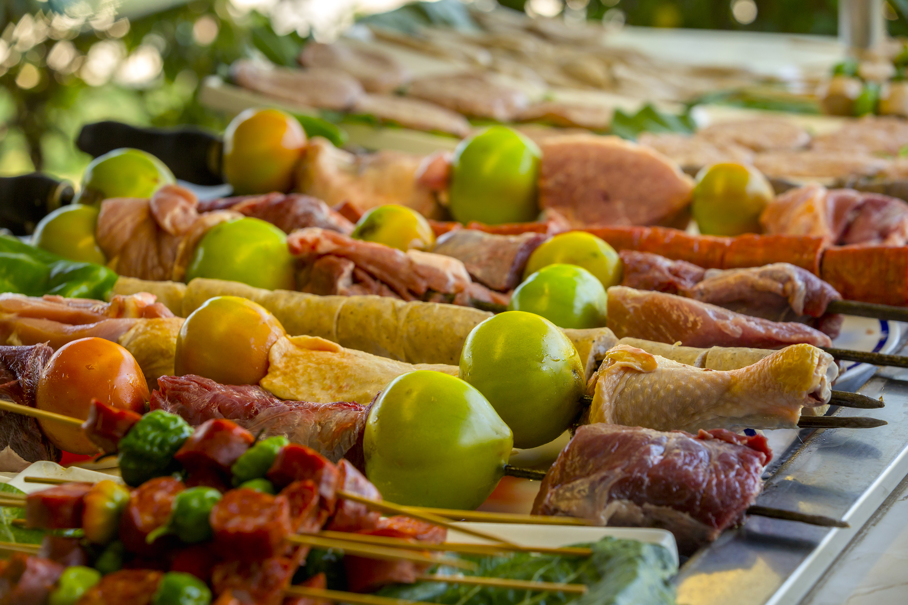 Raw meat, chicken, sausage, and vegetable skewers ready for grilling.