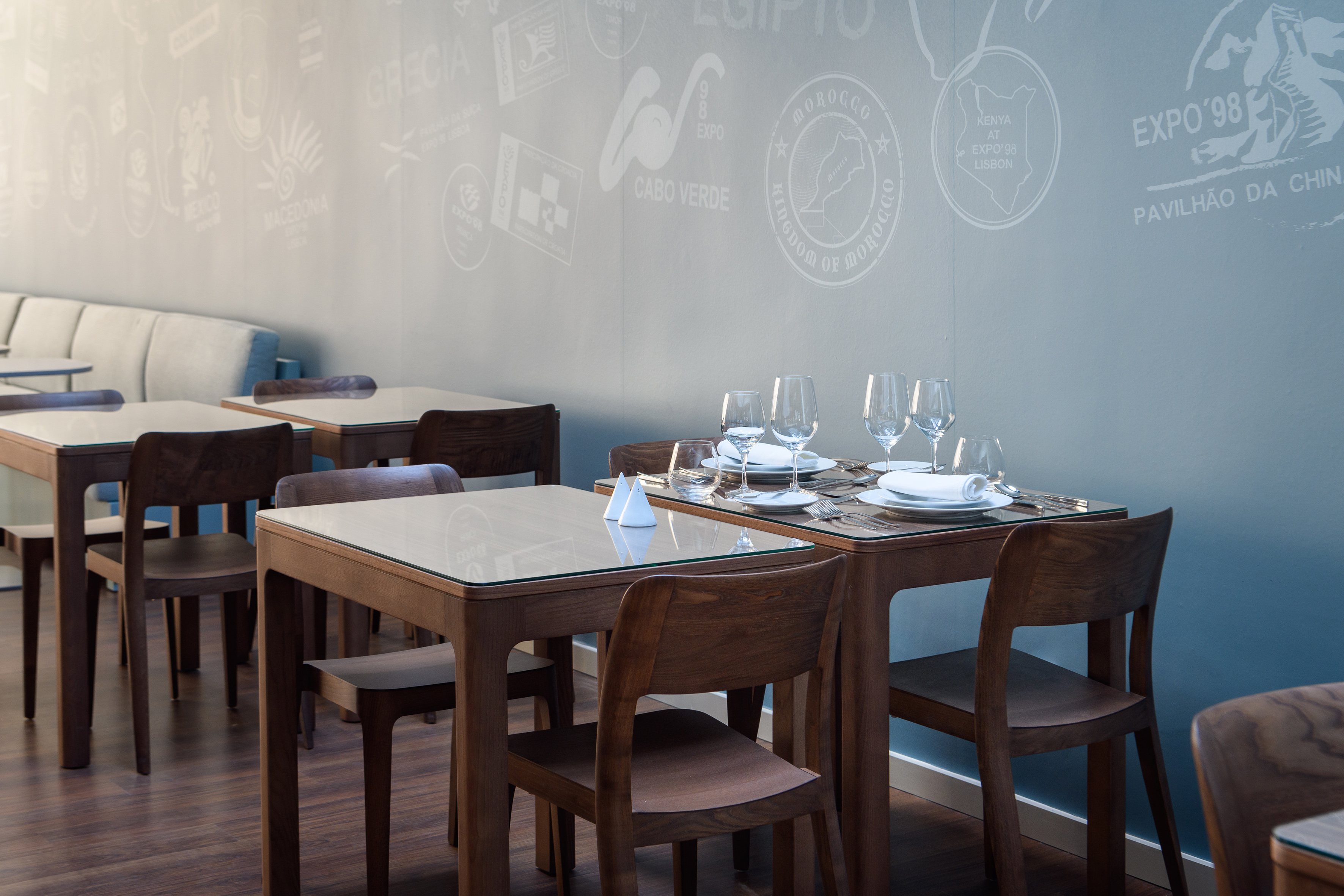 Restaurant with wooden tables, place settings, and Expo '98 themed wall.