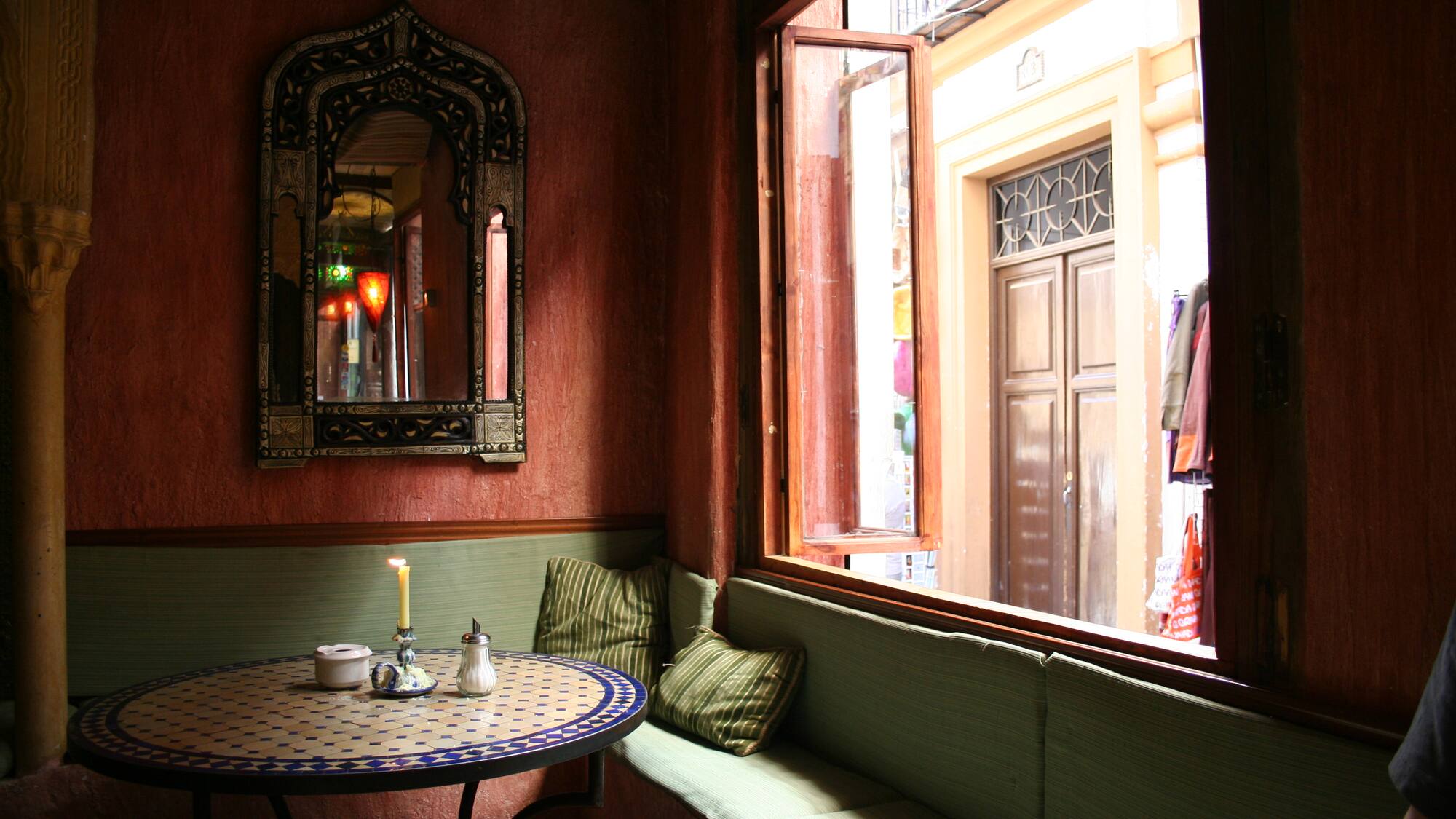 a table with candles and a mirror in a room with a window