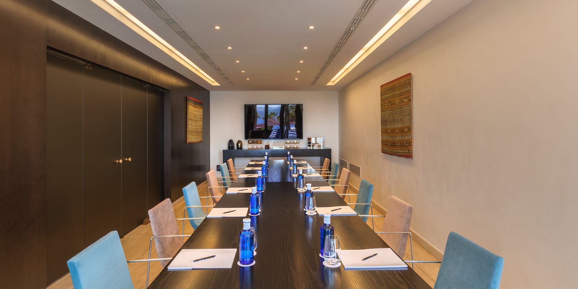 a long conference table with blue chairs and a black table