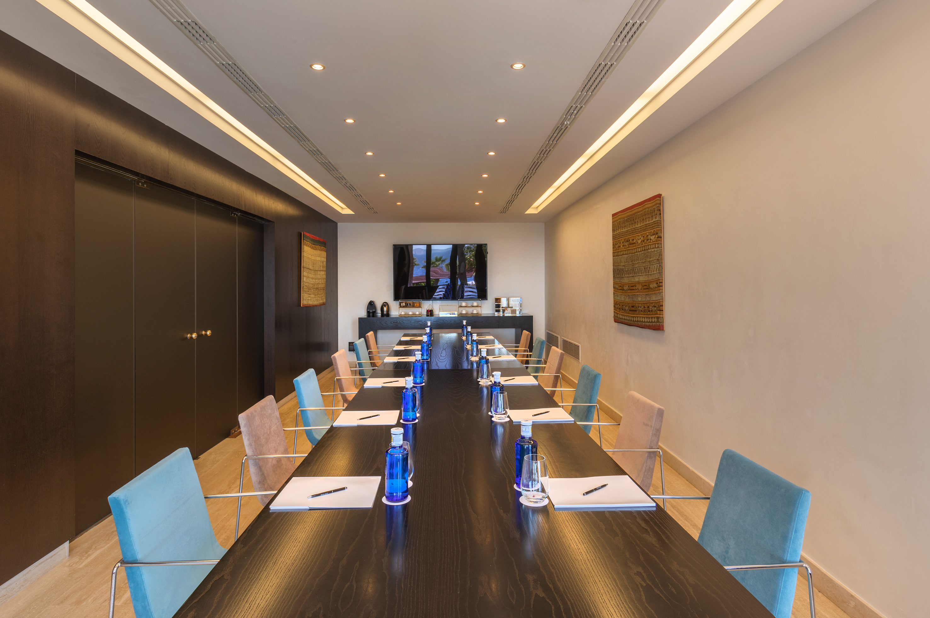 a long conference table with blue chairs and a black table
