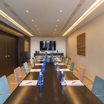 a long conference table with blue chairs and a black table