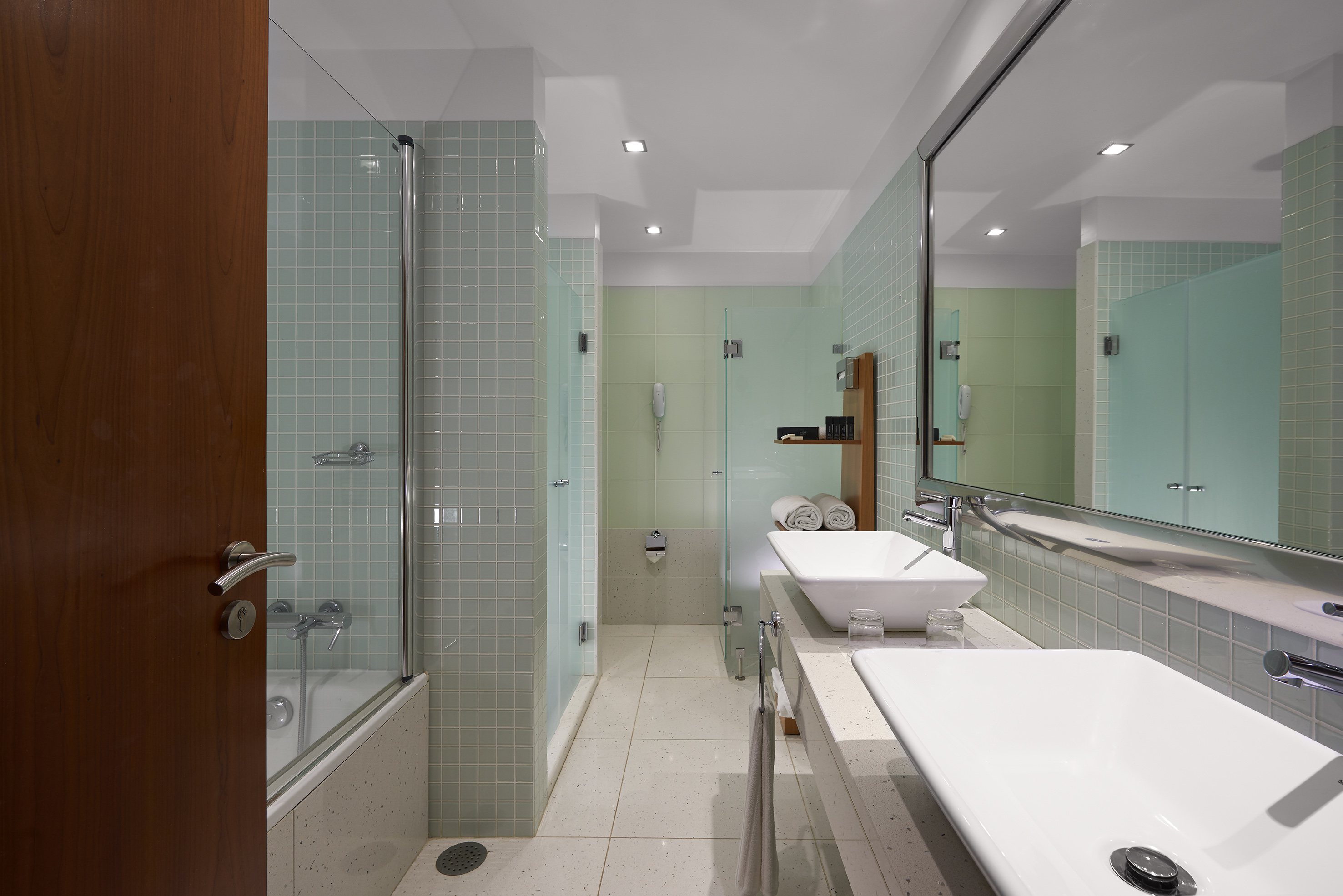 Modern hotel bathroom with double vanity, vessel sinks, shower, and tub.