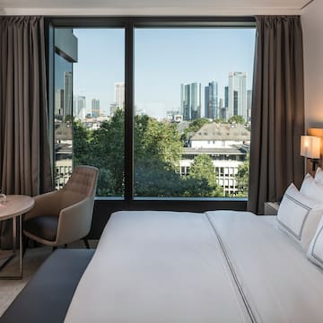 a hotel room with a large window and a city view