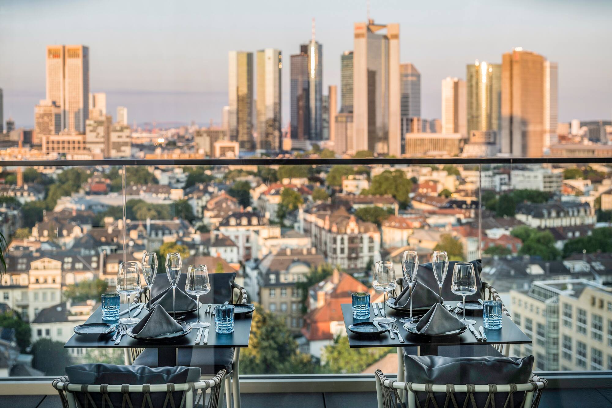 Modern rooftop restaurant tables set overlooking the Frankfurt skyline.