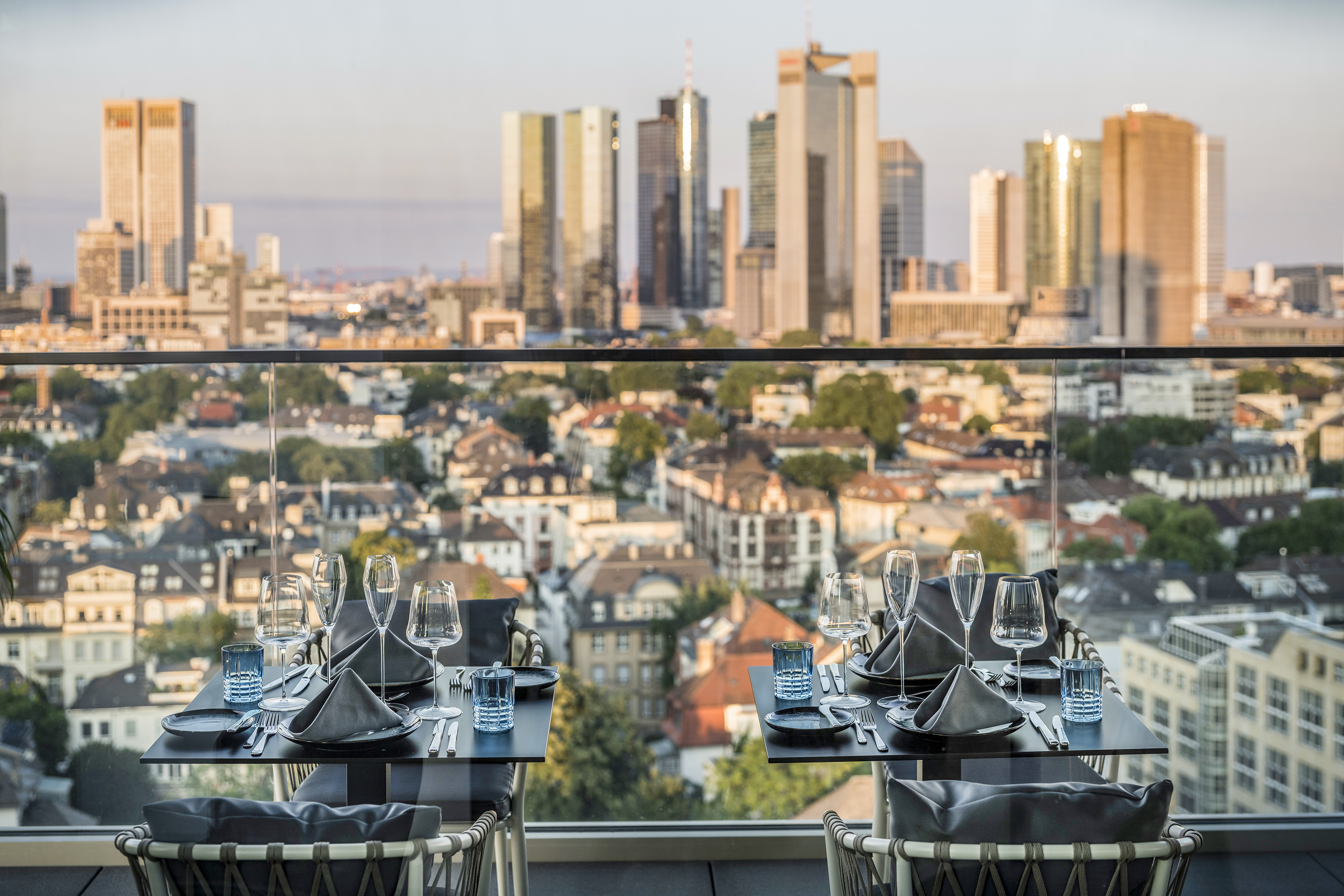 Modern rooftop restaurant tables set overlooking the Frankfurt skyline.