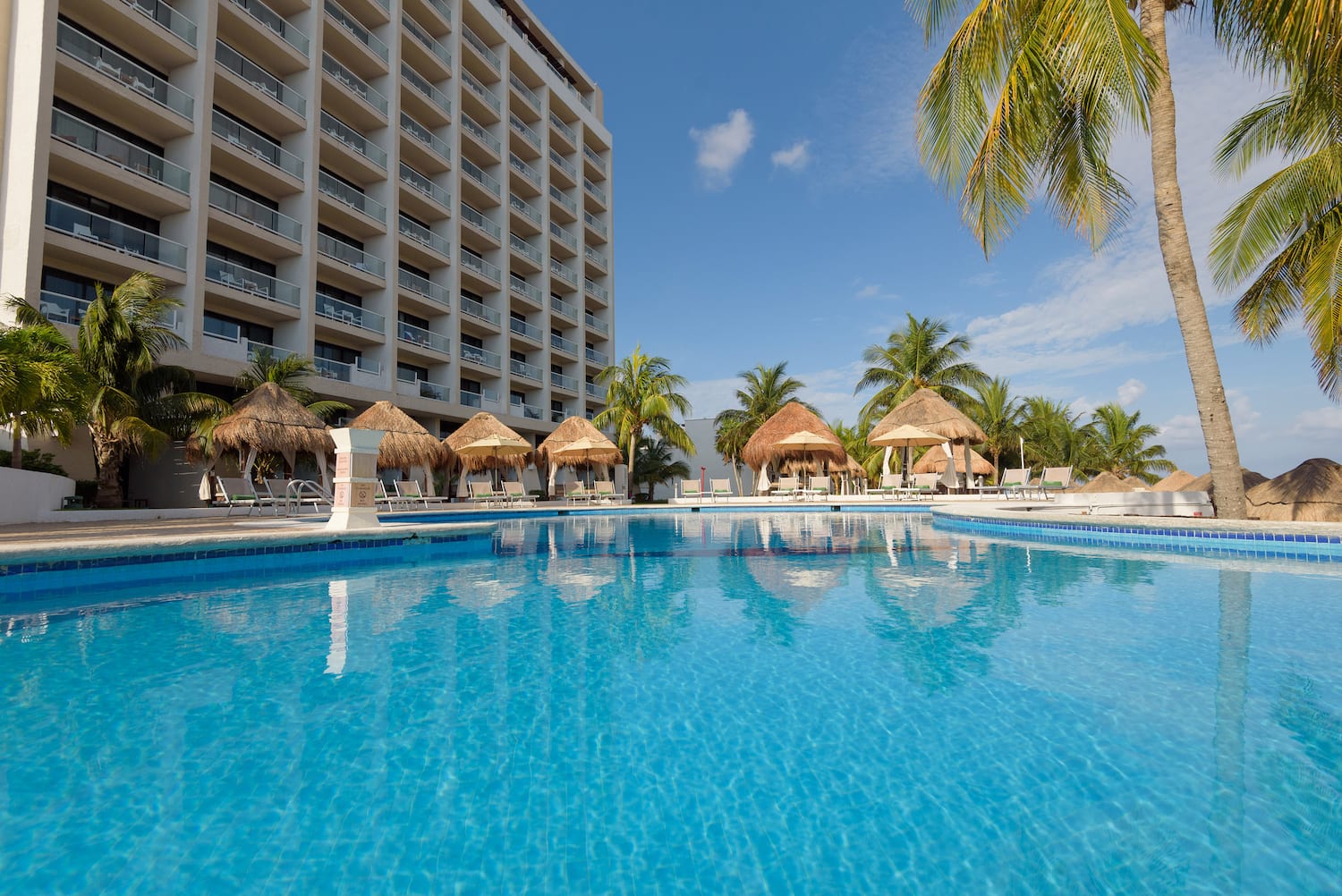a pool with straw umbrellas and palm trees