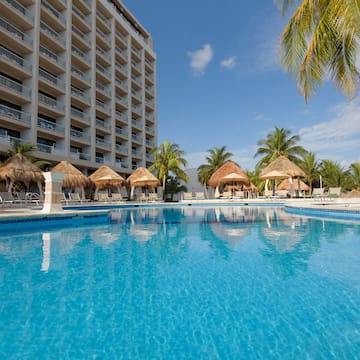 a pool with straw umbrellas and palm trees