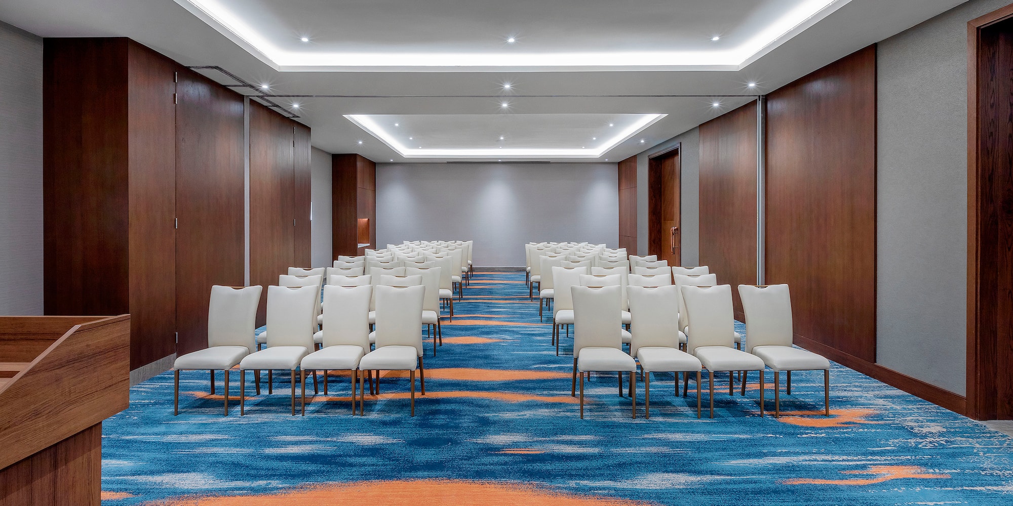 a room with white chairs and blue carpet