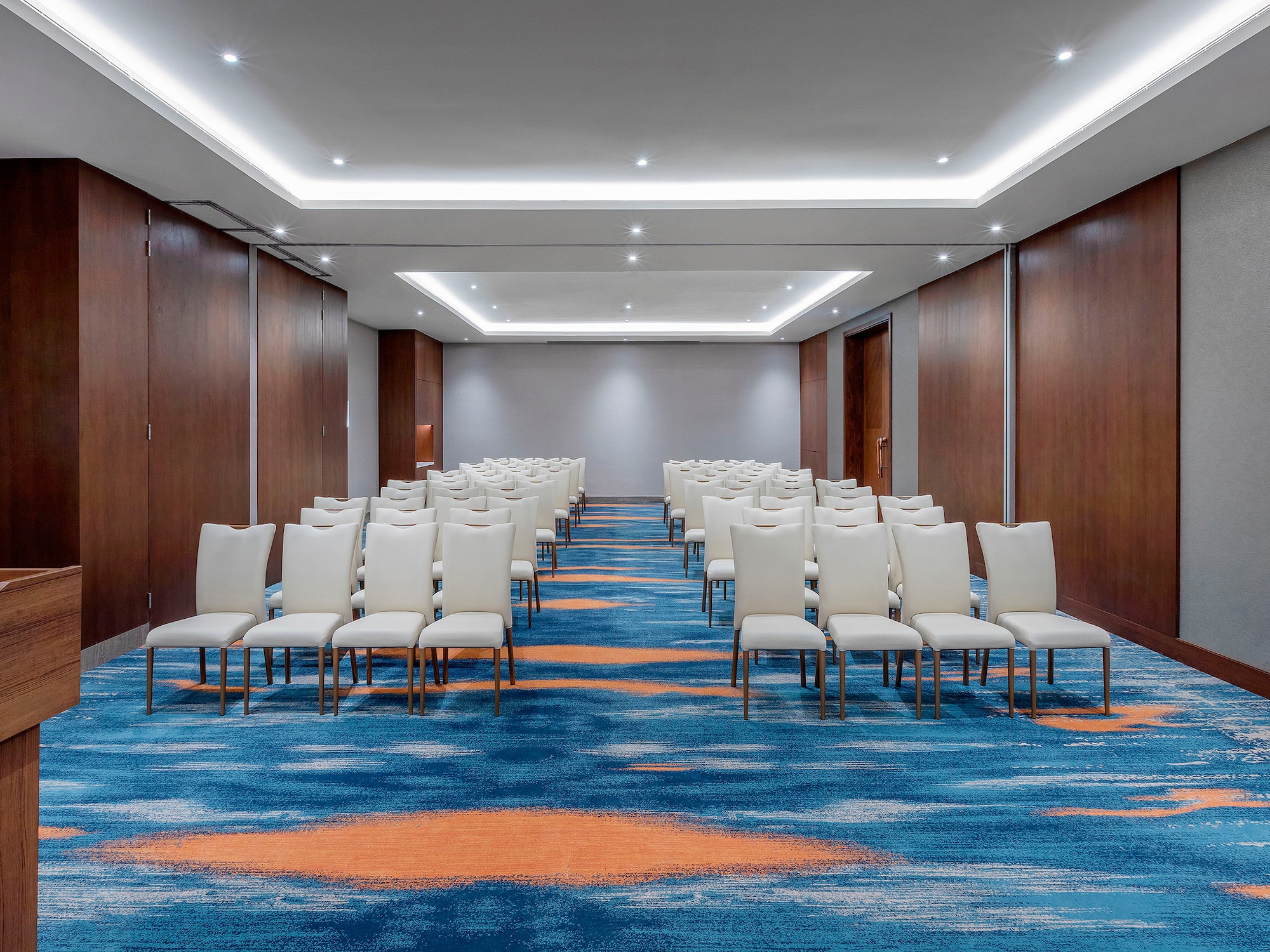 a room with white chairs and blue carpet