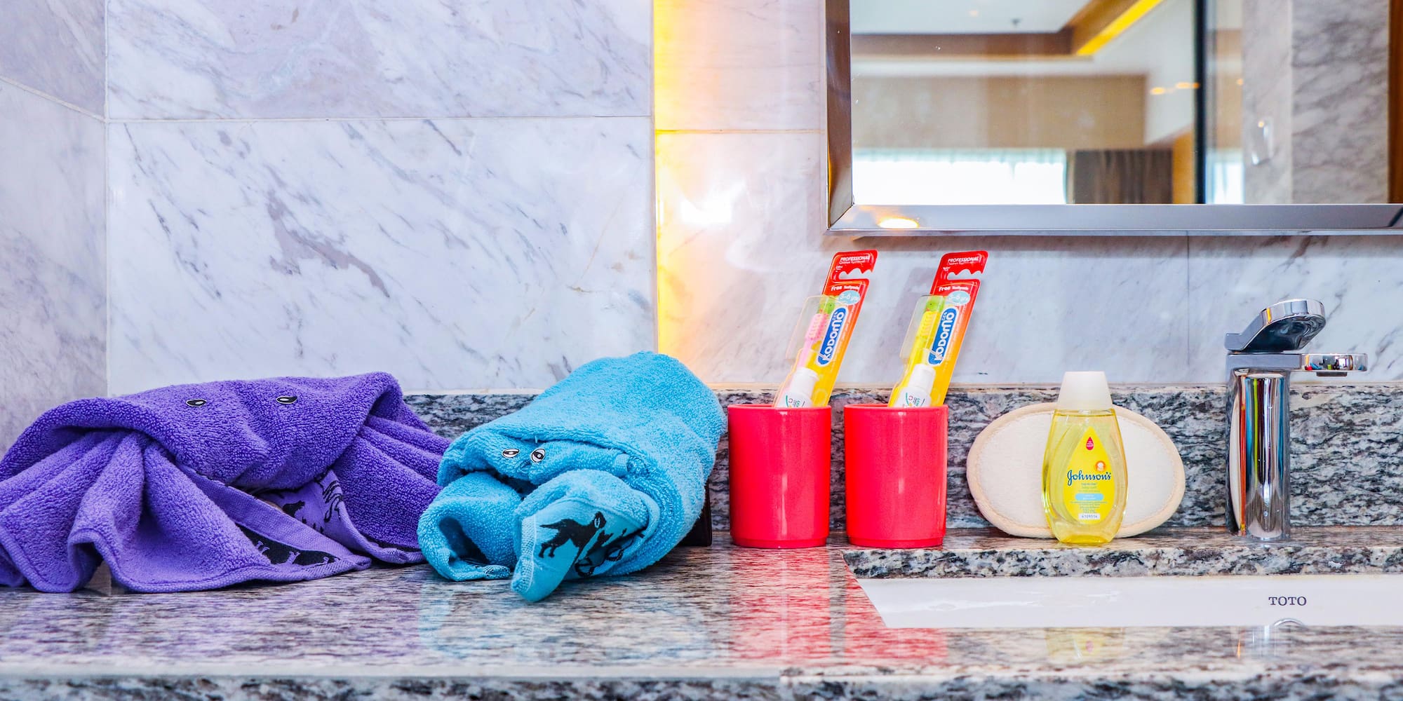 a bathroom sink with towels and toothpaste