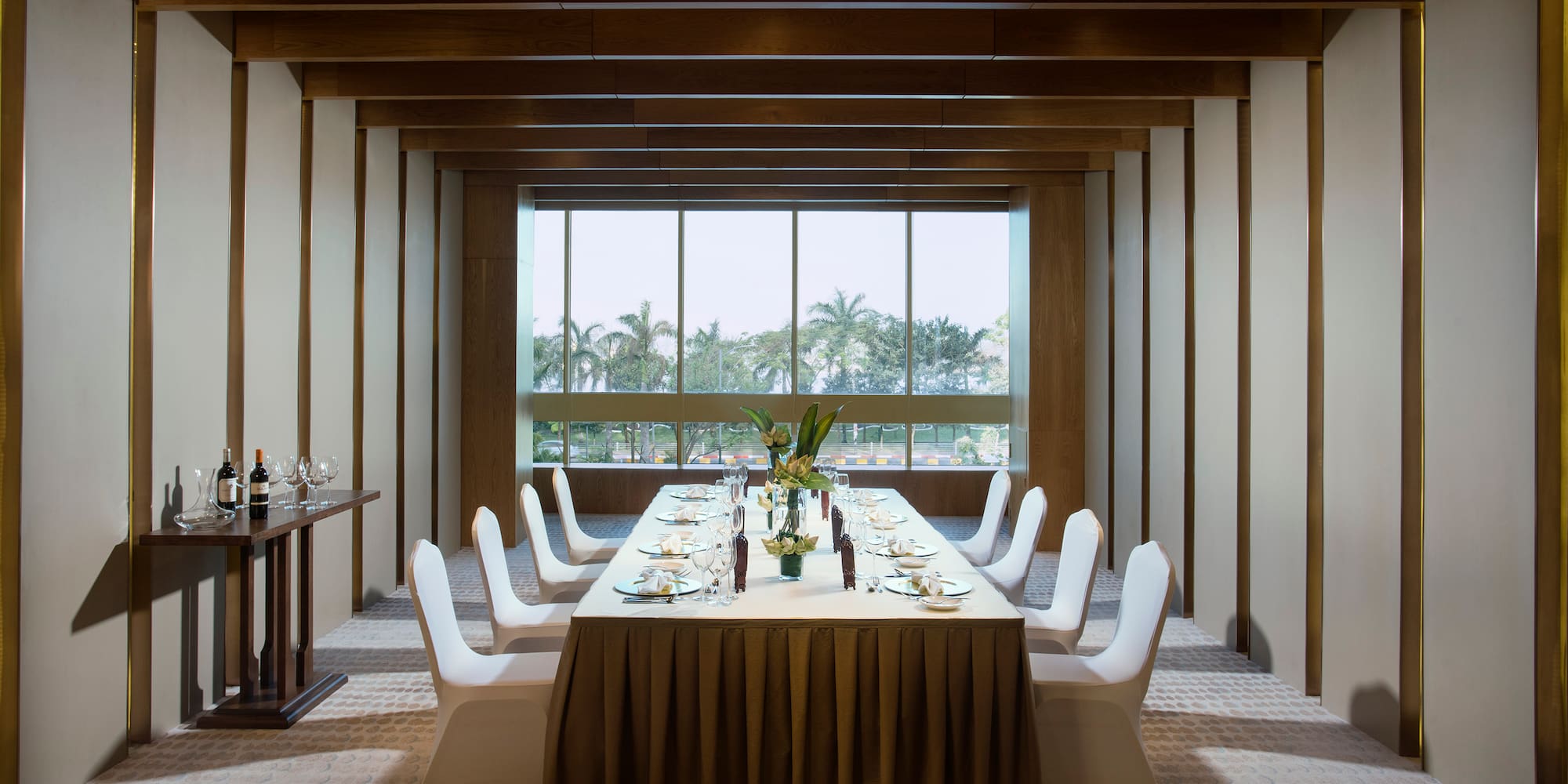 a long table with white chairs and plates