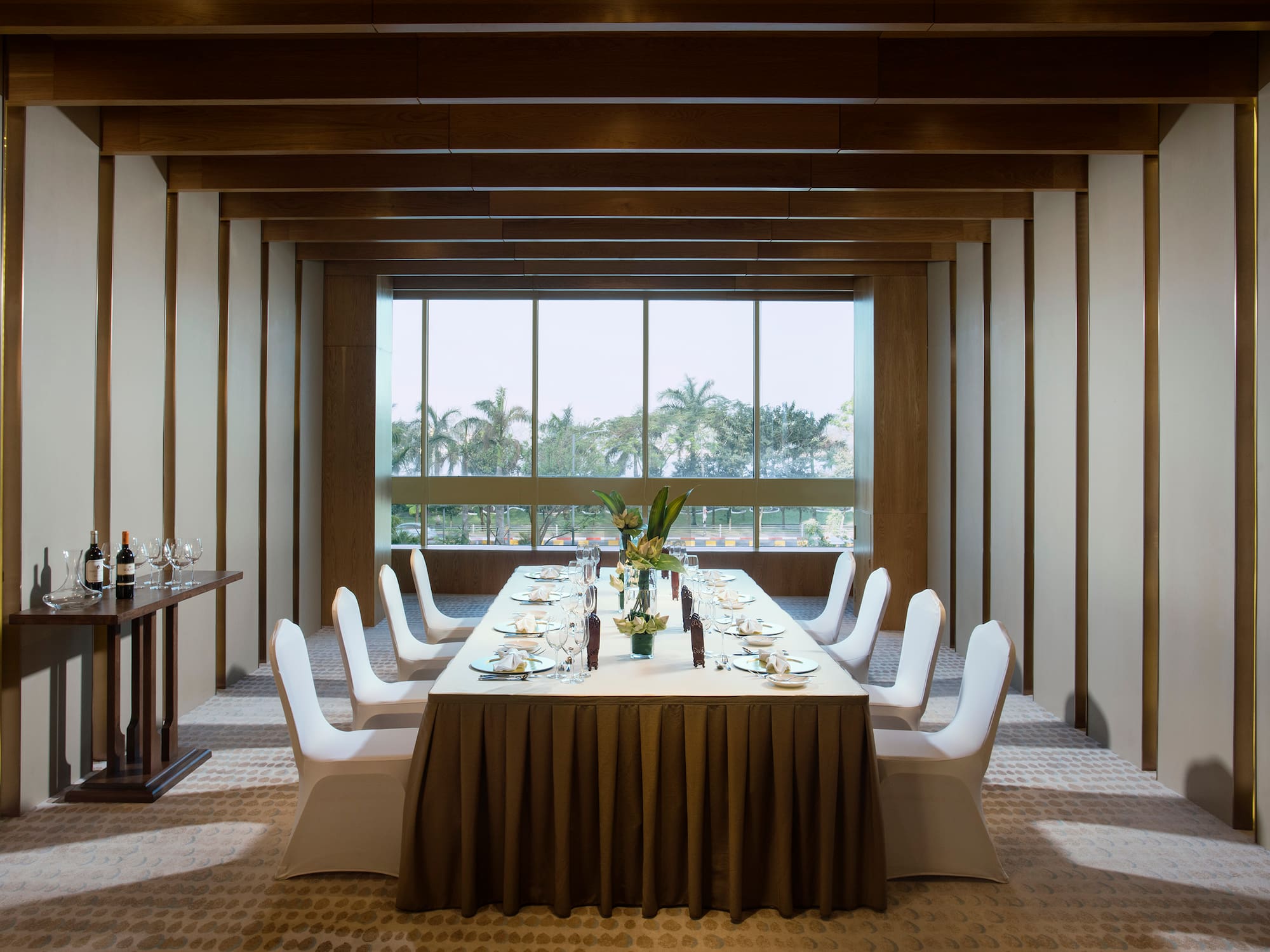 a long table with white chairs and plates