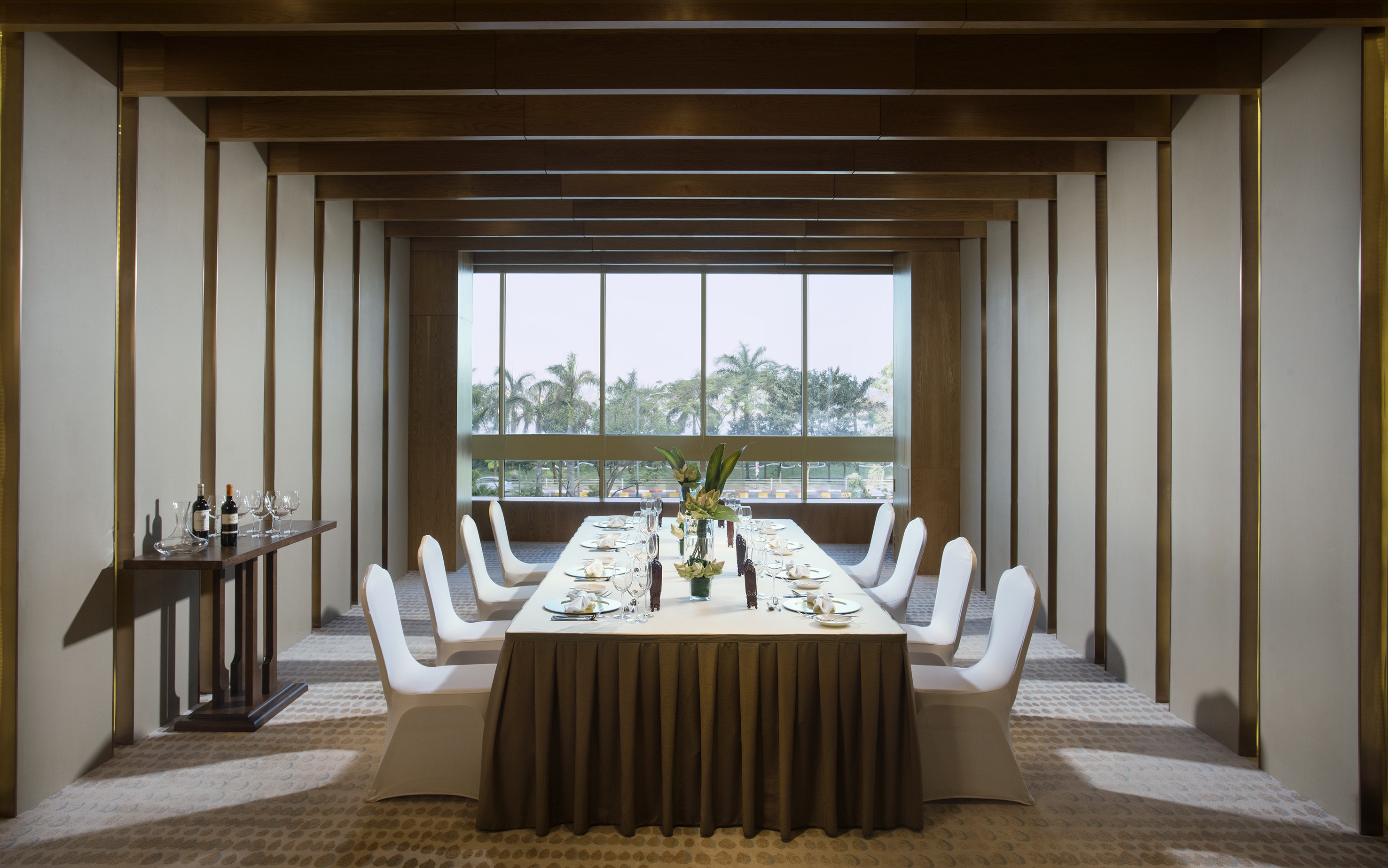 Formal private dining room with set table, wine, and outdoor tropical view.