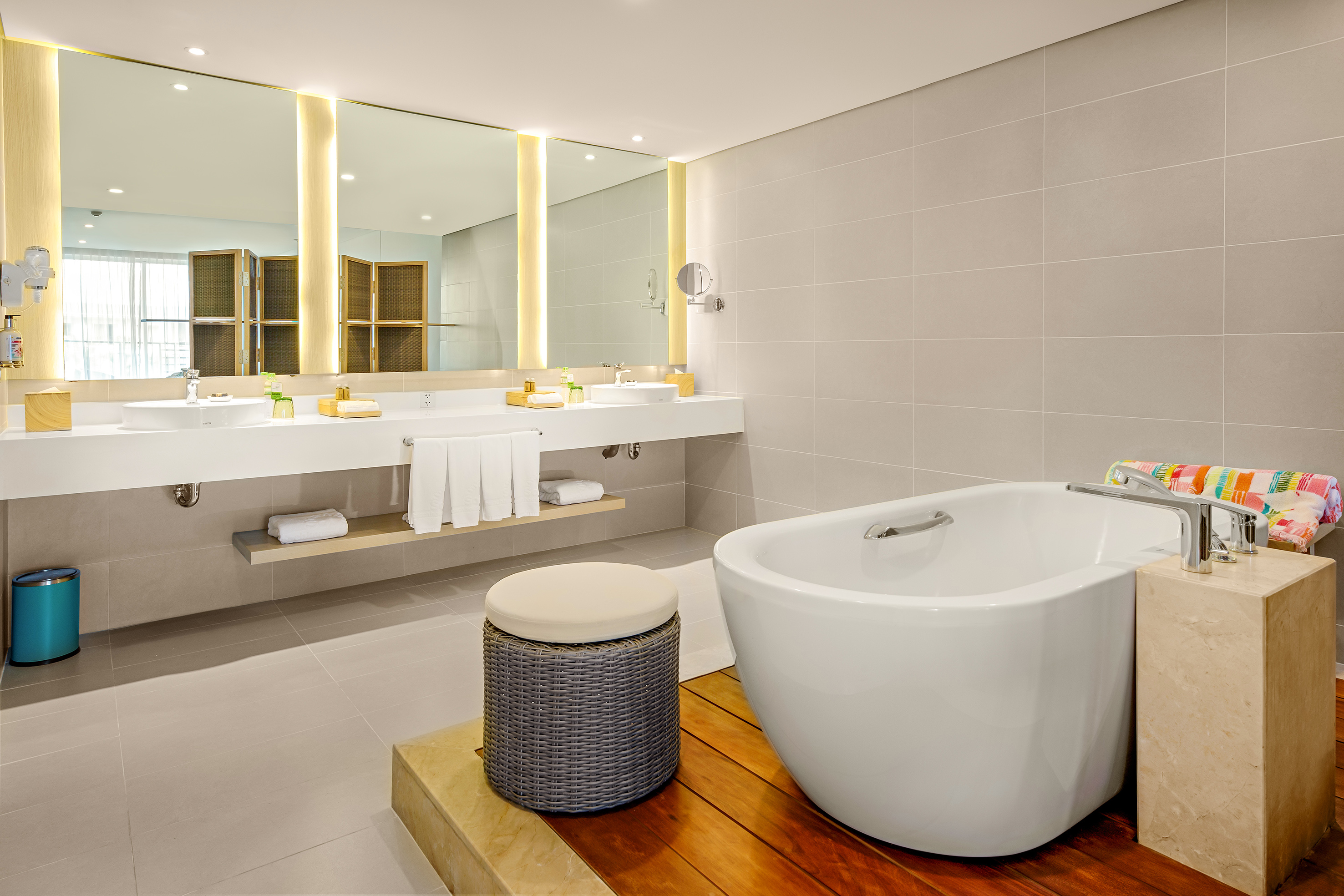 Modern bathroom with double vanity, illuminated mirrors, and freestanding tub.