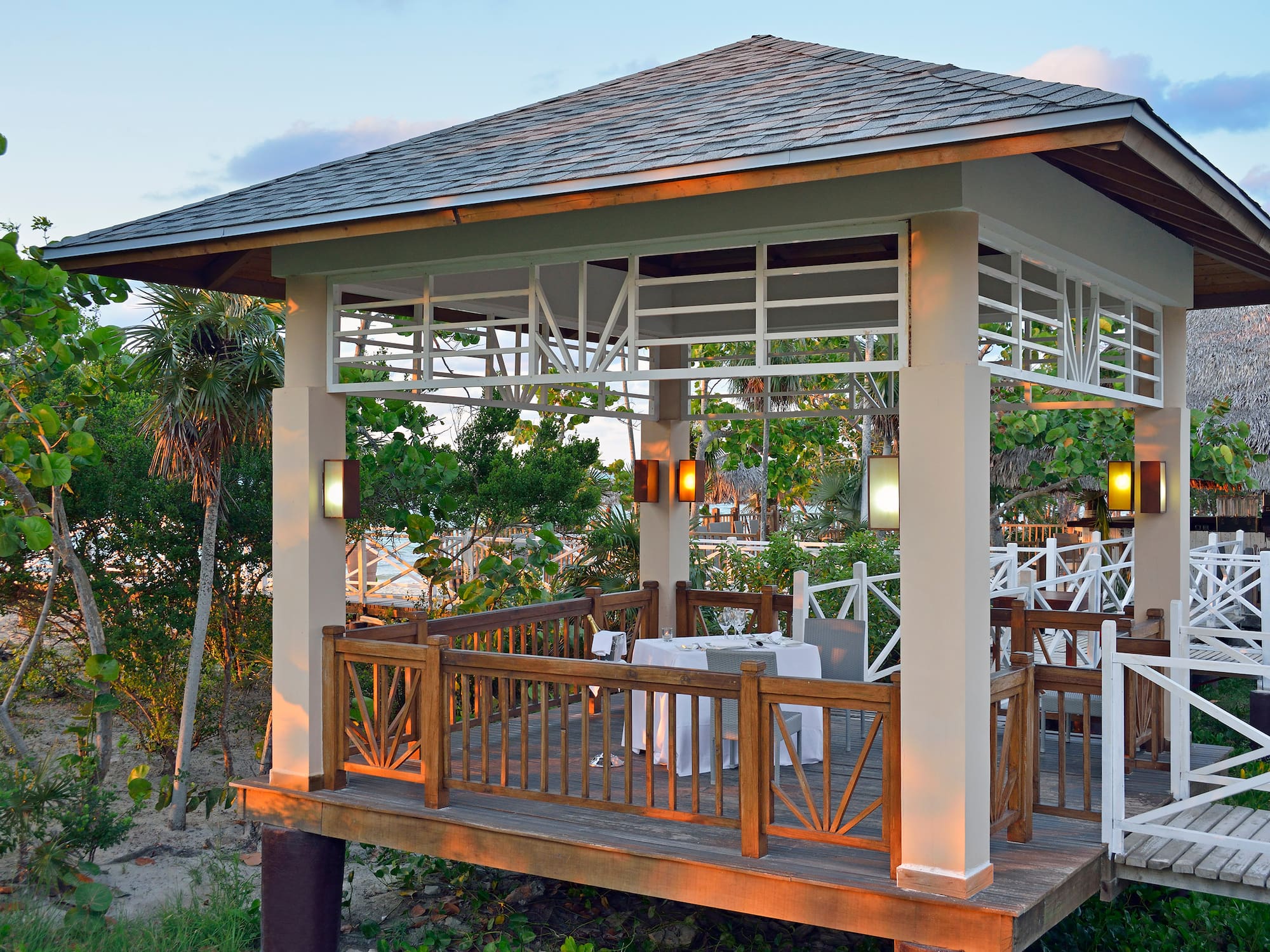 a gazebo with tables and chairs under a tree