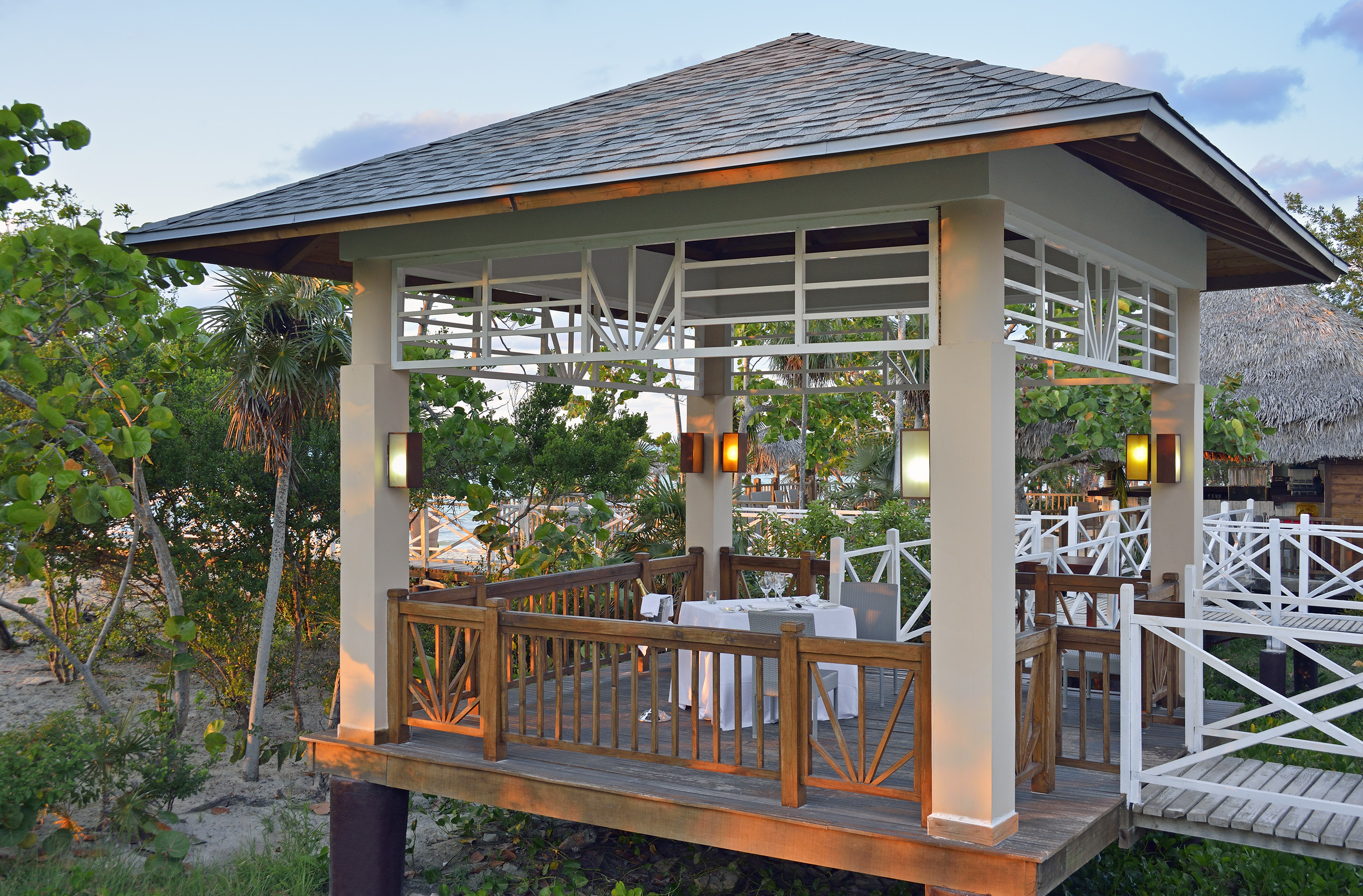 a gazebo with tables and chairs under a tree