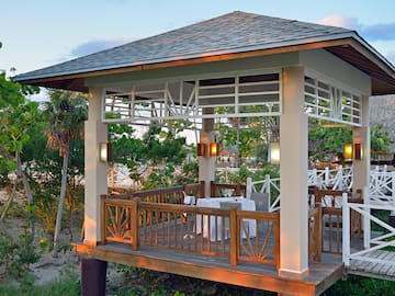 a gazebo with tables and chairs under a tree