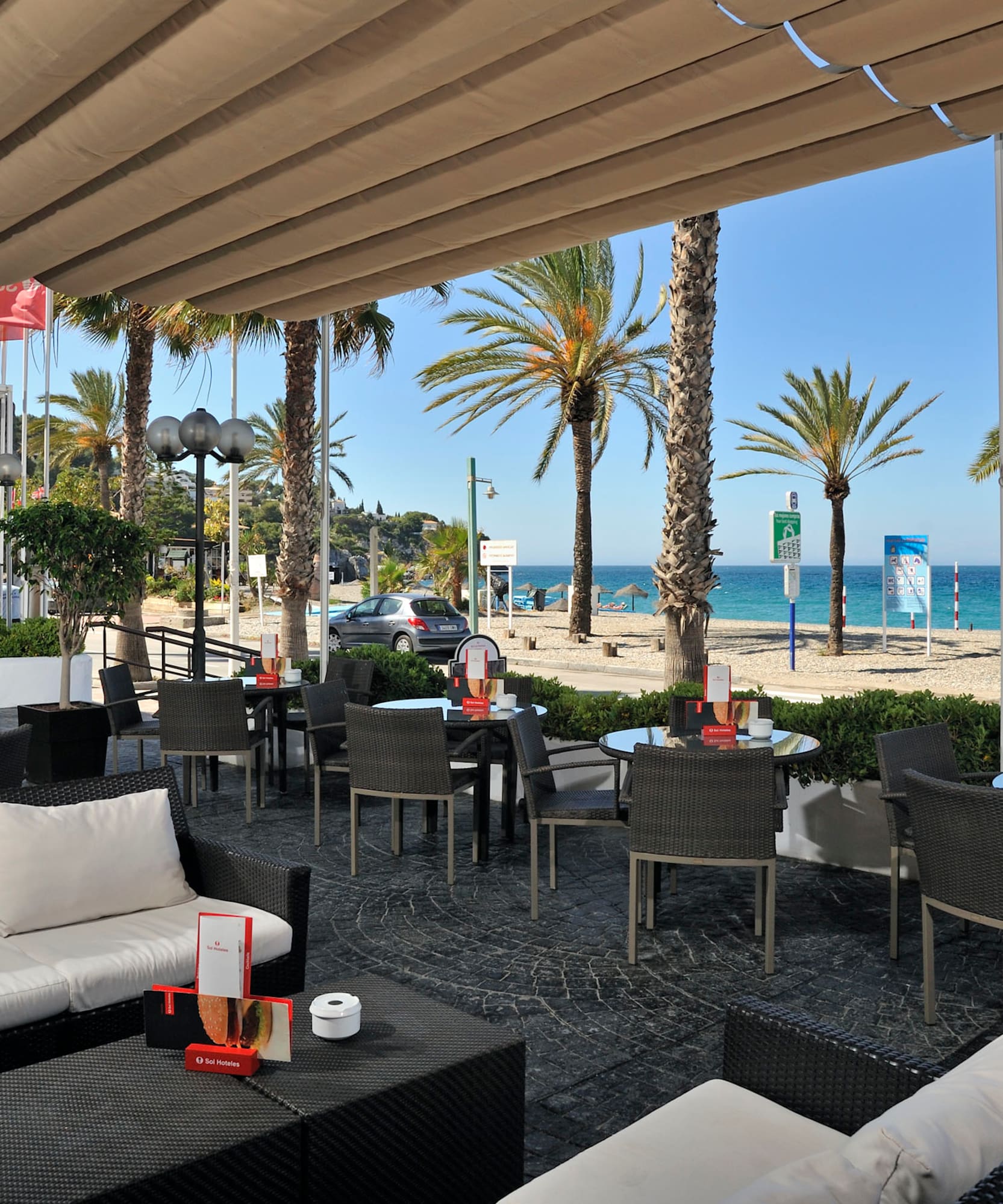 a patio with chairs and tables and a beach