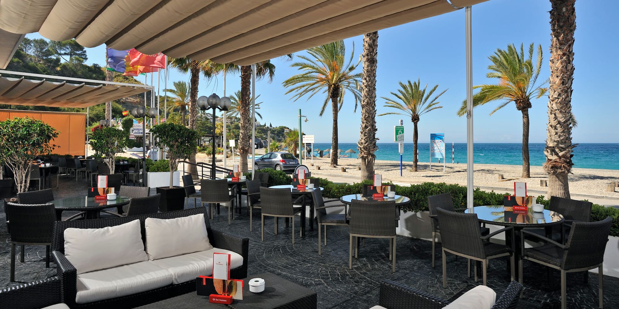 a patio with chairs and tables and a beach
