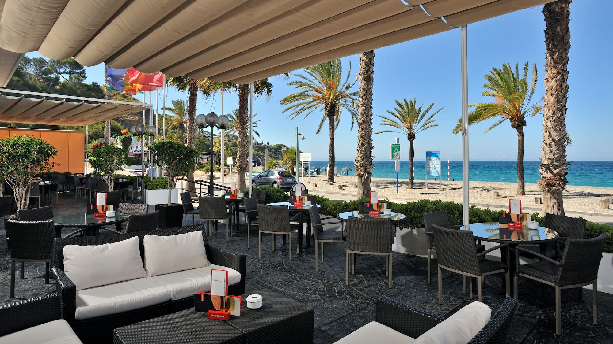 a patio with chairs and tables and a beach