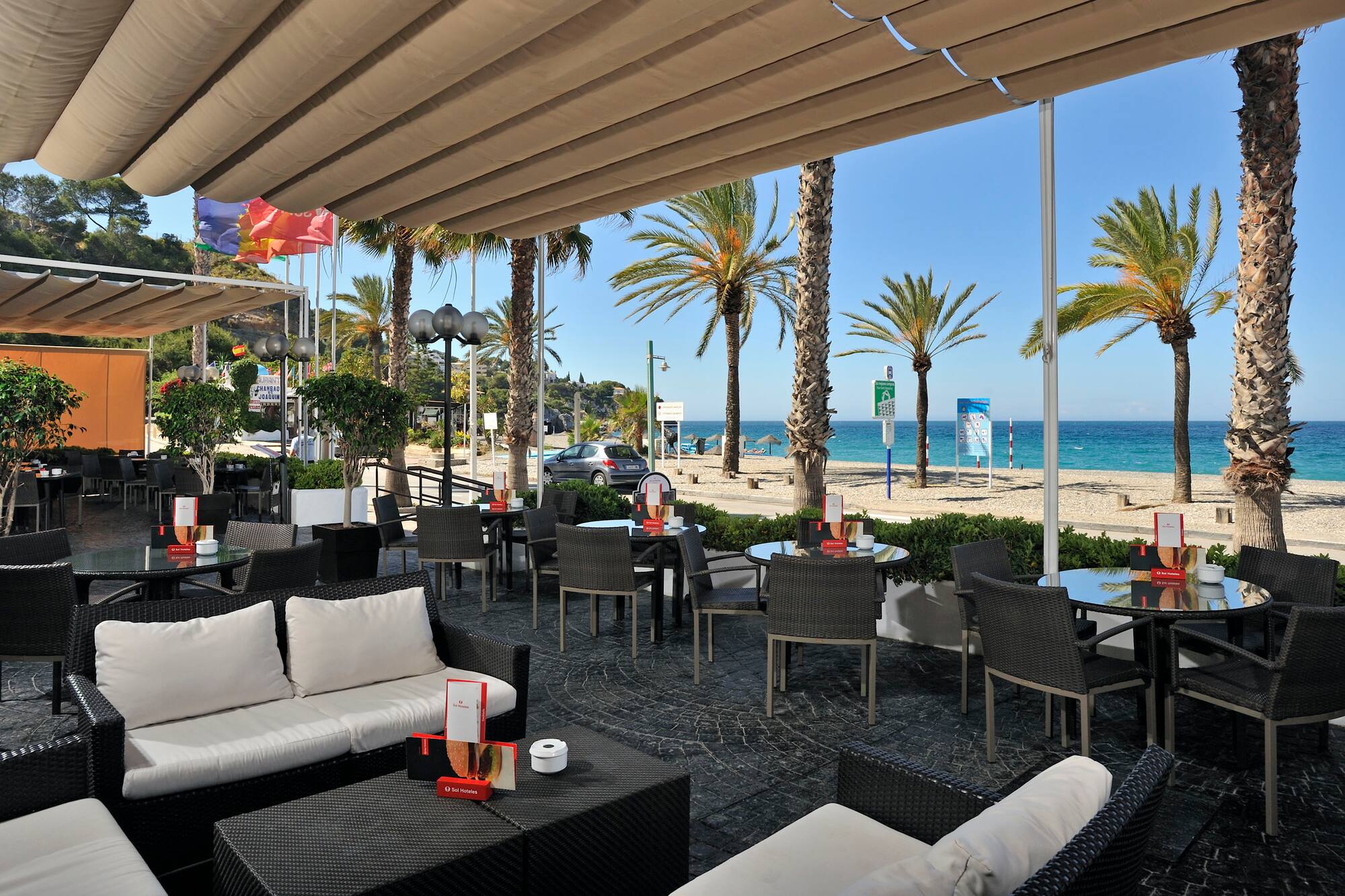 a patio with chairs and tables and a beach