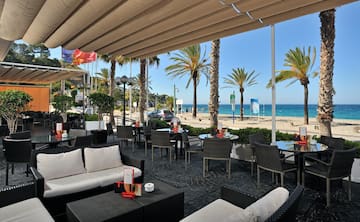 a patio with chairs and tables and a beach