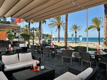 a patio with chairs and tables and a beach