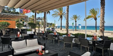 a patio with chairs and tables and a beach