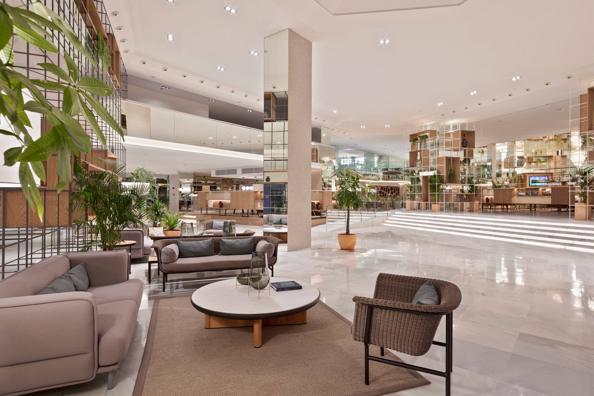 Biophilic hotel lobby with modern seating, marble floor, and abundant green plants.