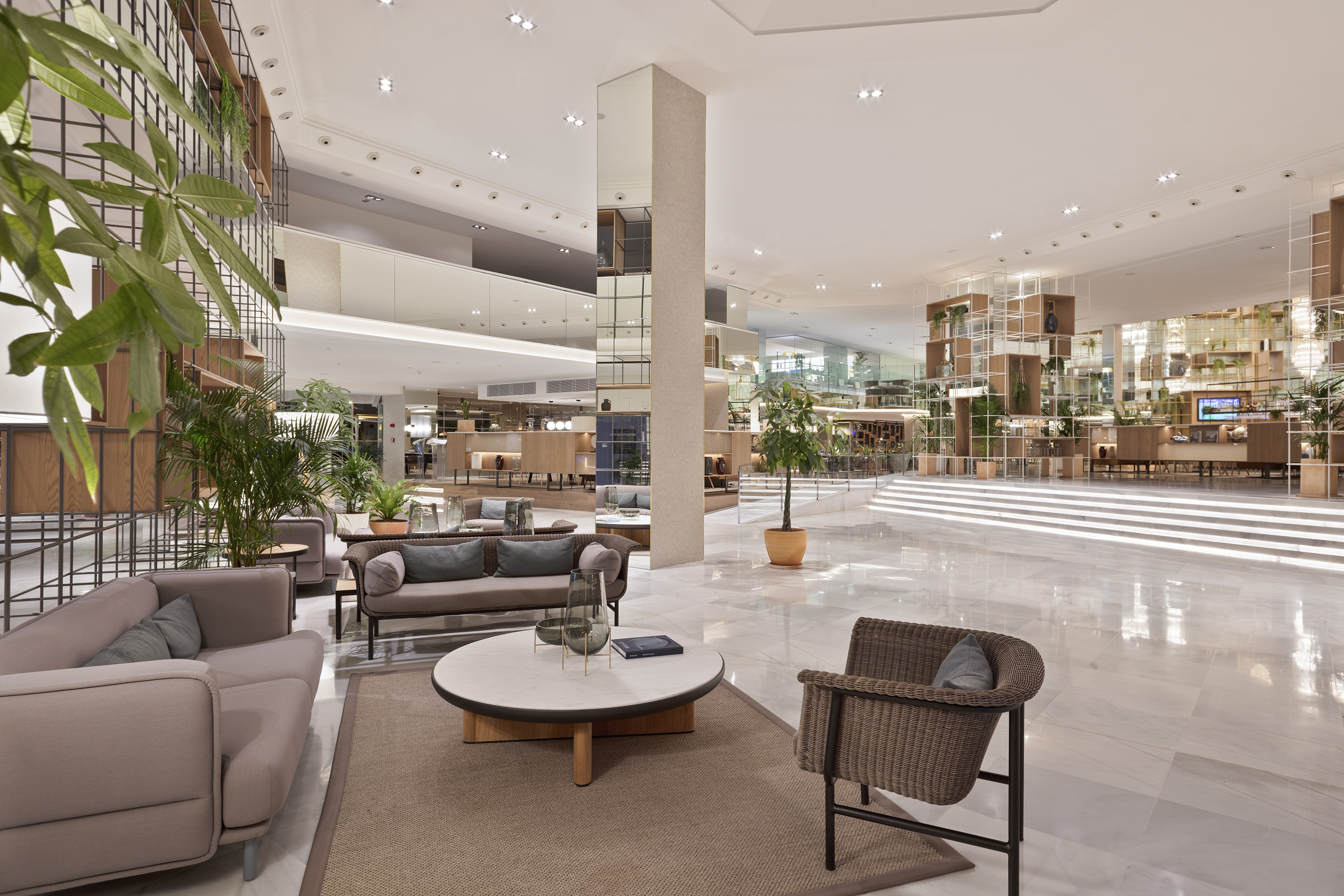 Biophilic hotel lobby with modern seating, marble floor, and abundant green plants.