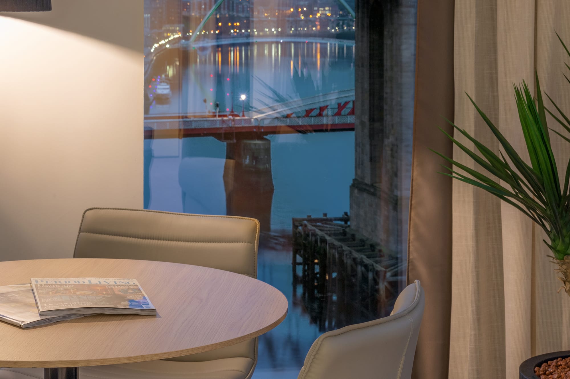 a table and chairs in a room with a bridge view through a window