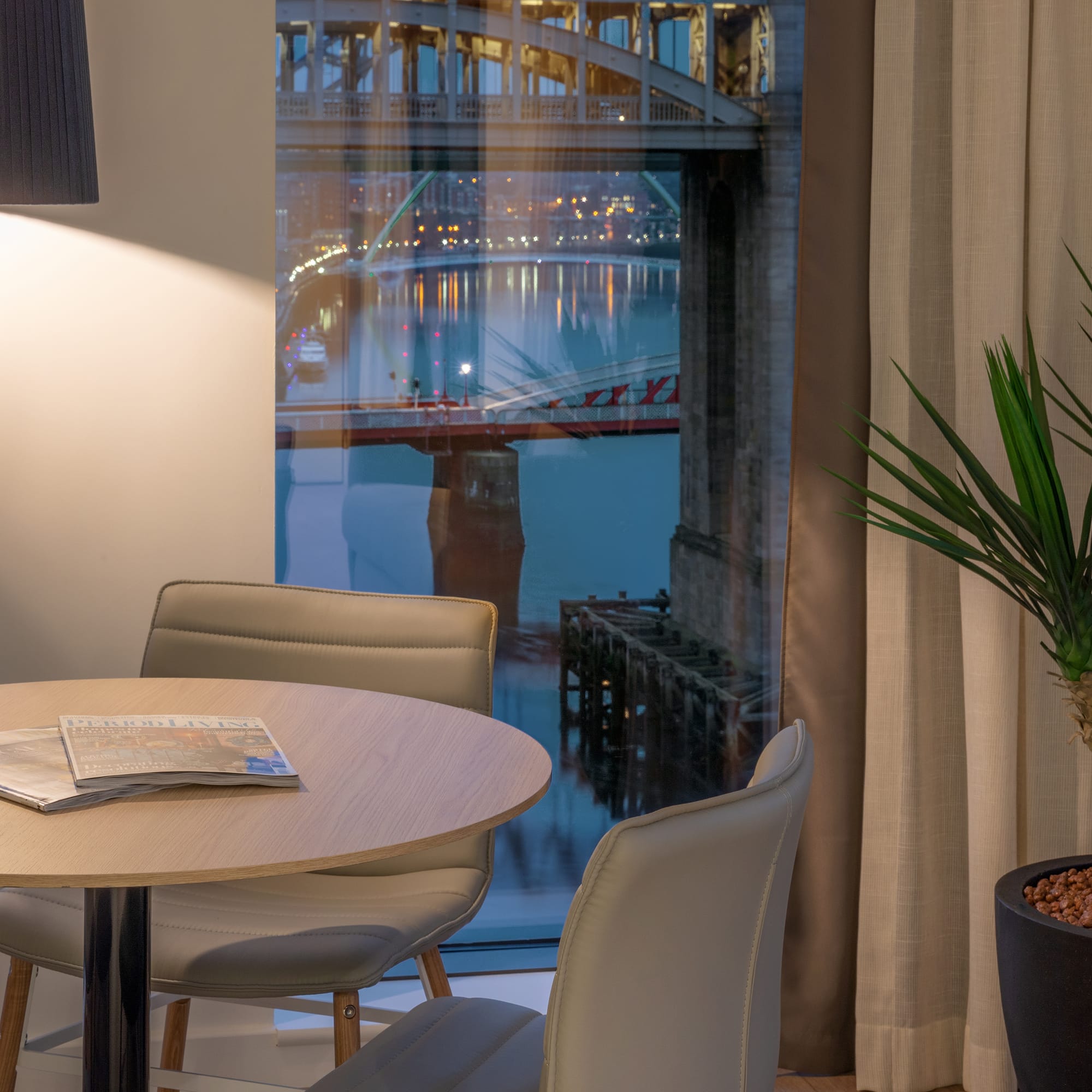a table and chairs in a room with a bridge view through a window