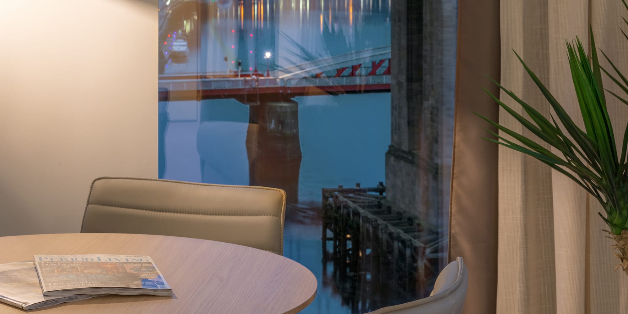 a table and chairs in a room with a bridge view through a window