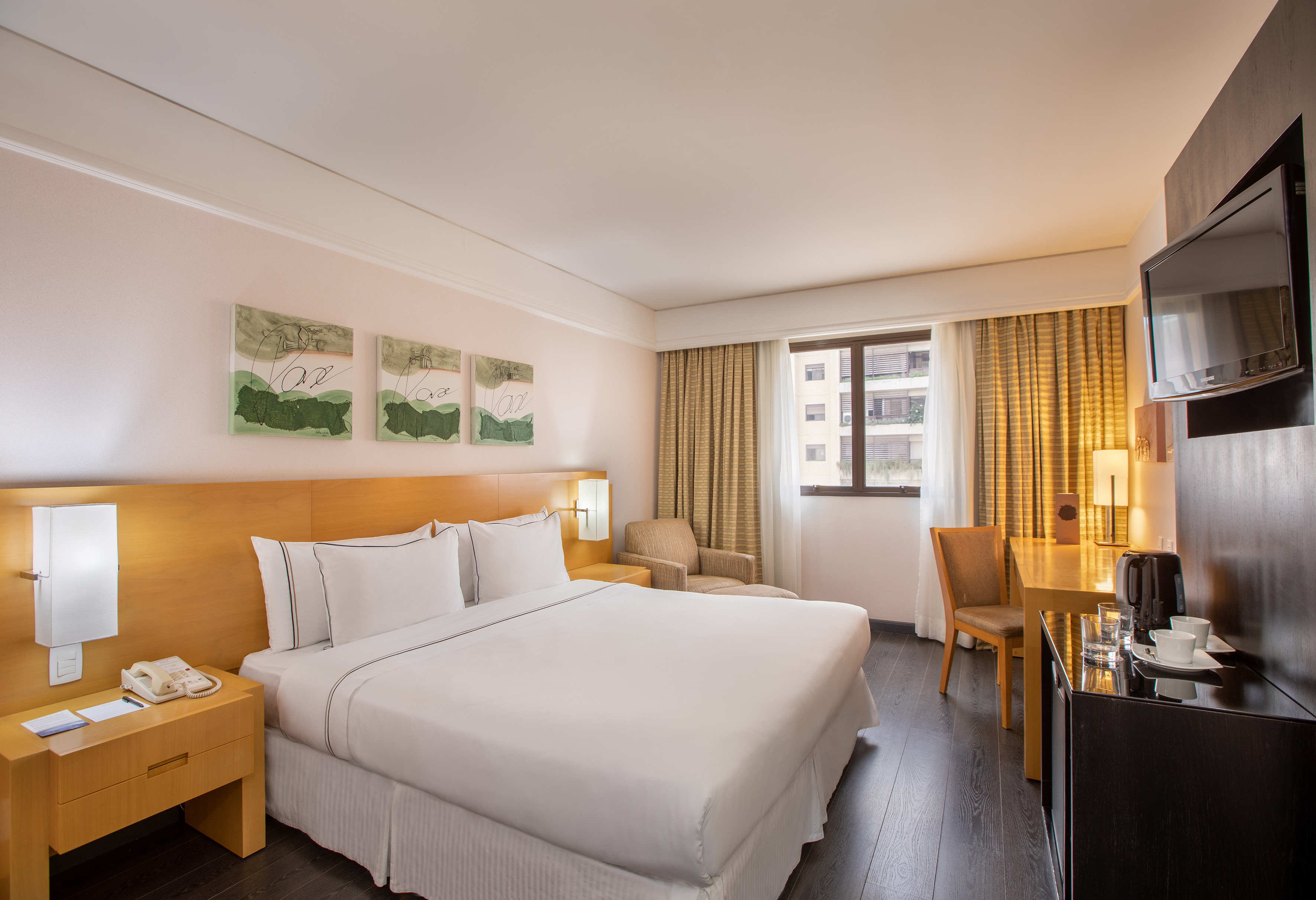 Stylish hotel room with comfortable bed, desk, TV, and window.