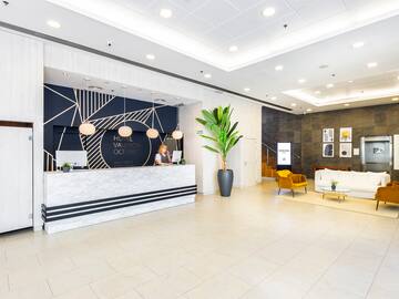 a lobby with a white and black reception desk and a plant