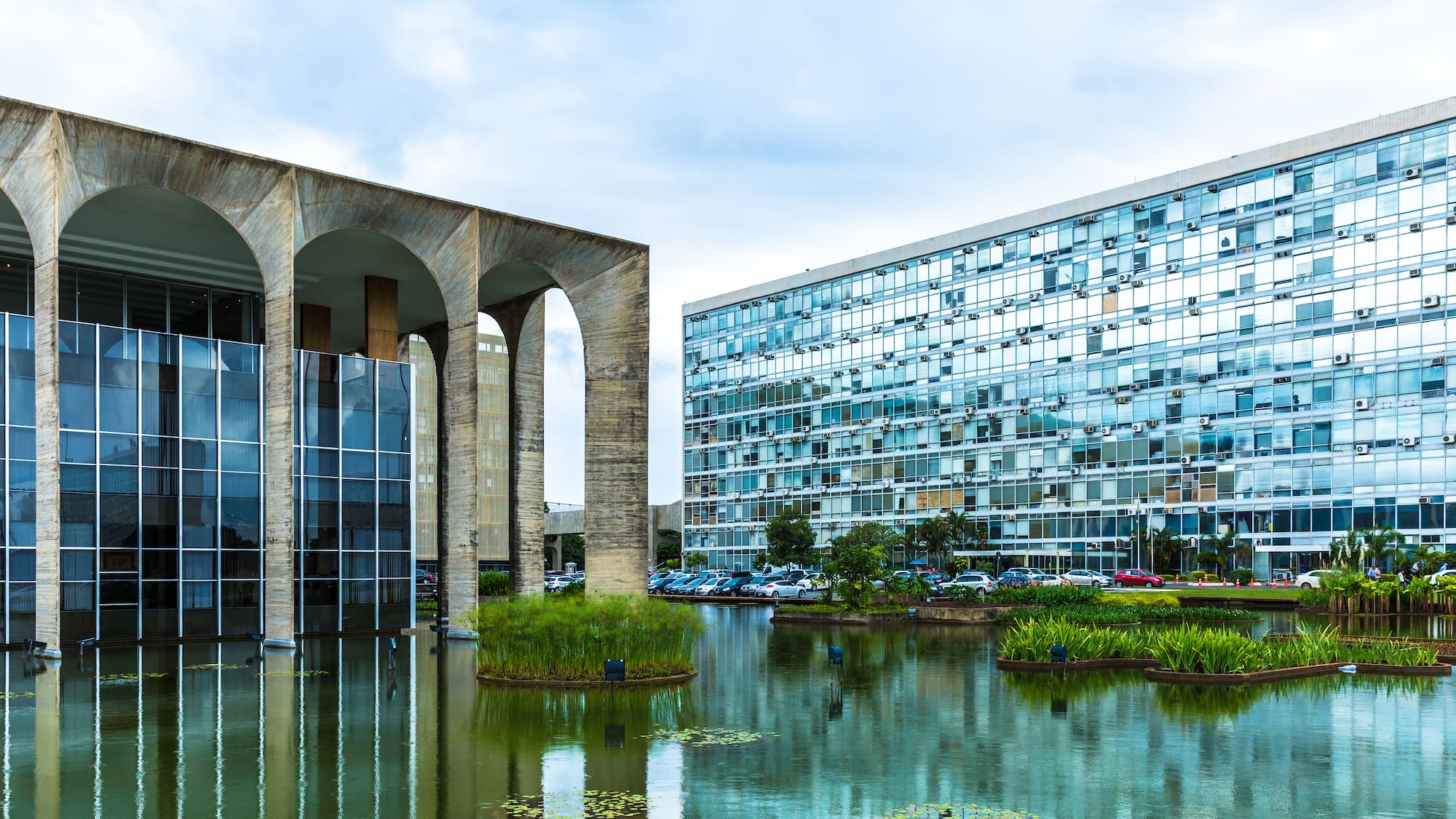 a building with a pond and plants in front of it