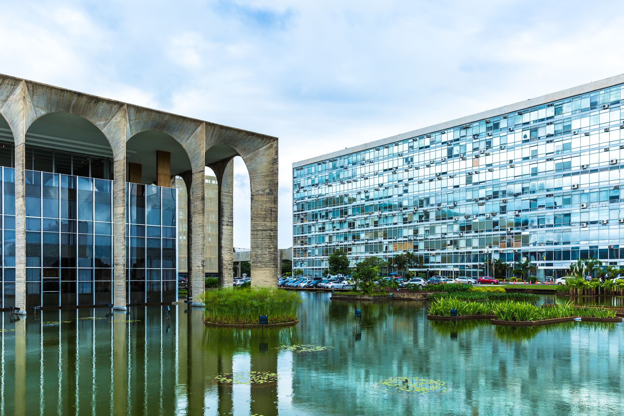 a building with a pond and plants in front of it