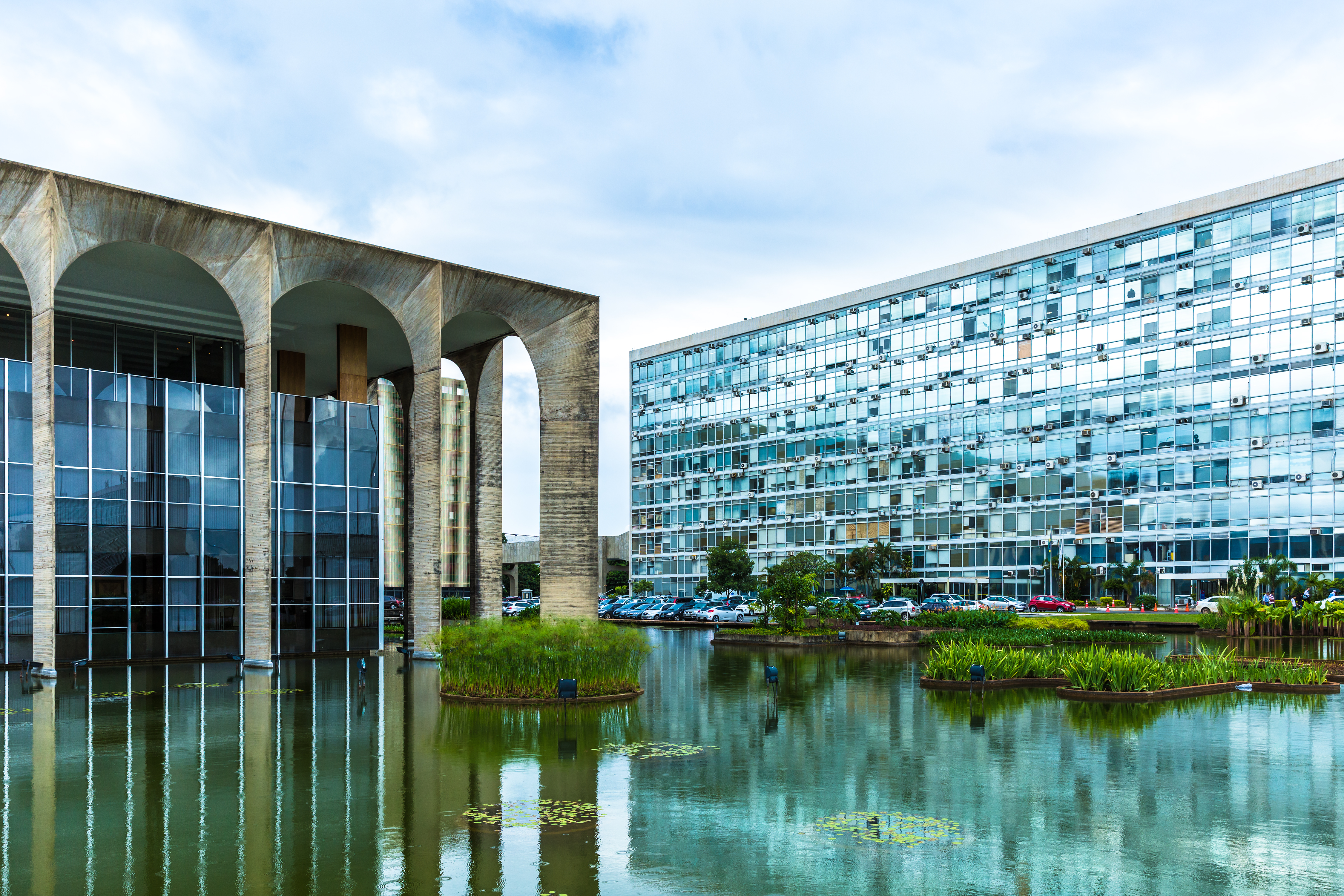 a building with a pond and plants in front of it