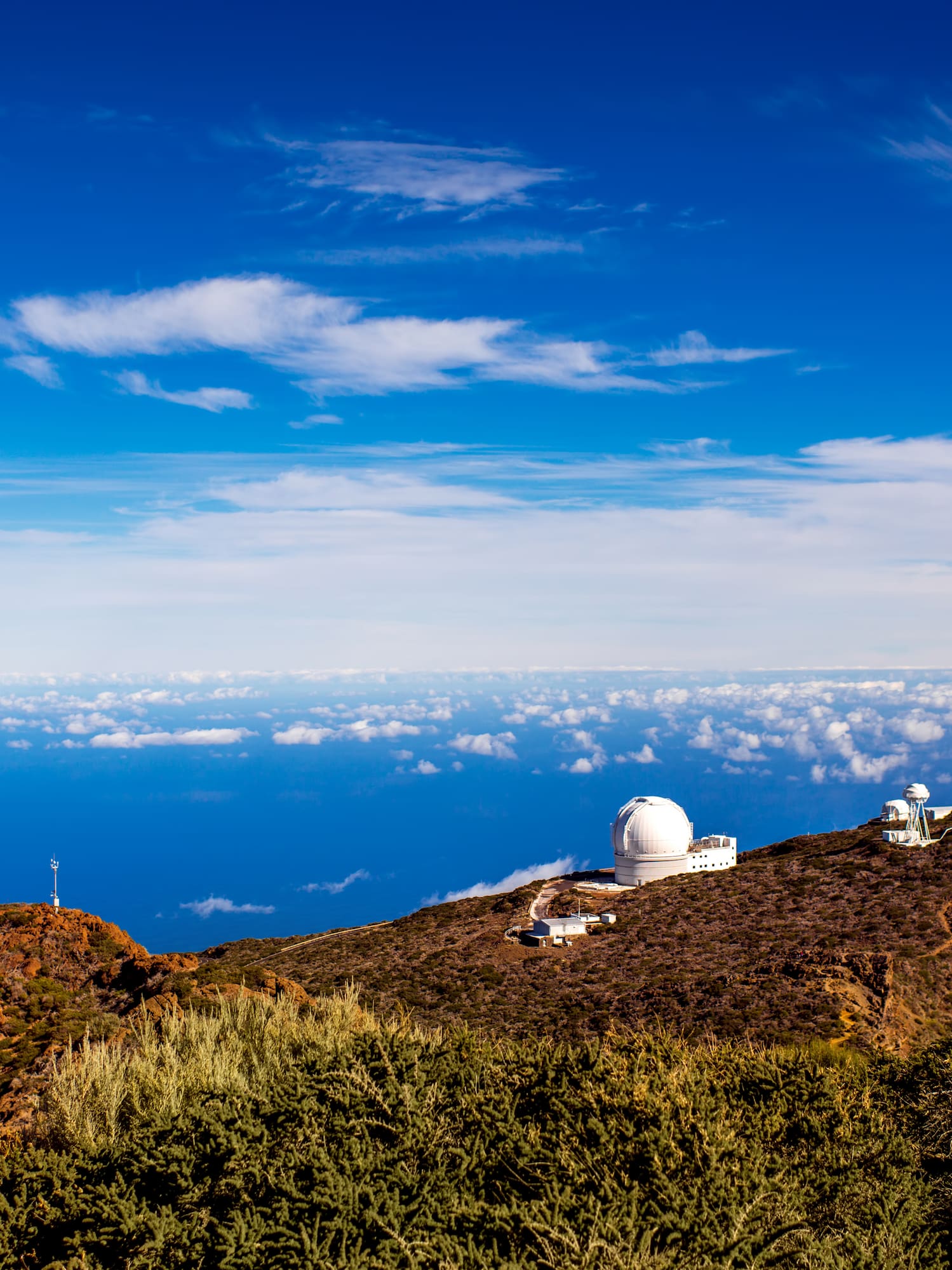 a view of a mountain with buildings and clouds in the sky.